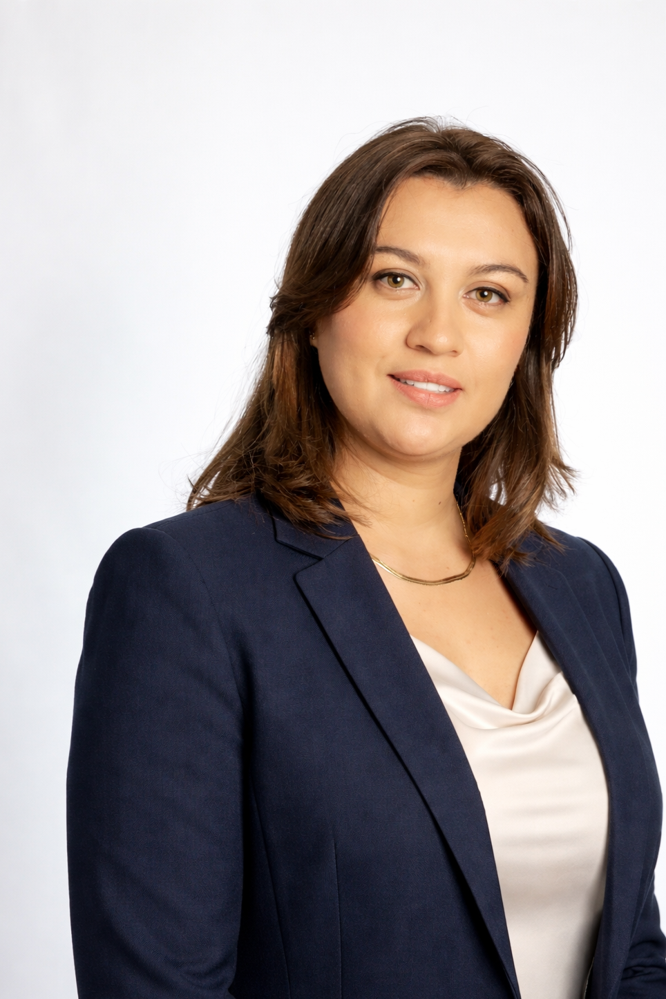 A smiling woman with long brown hair, wearing a black zip-up sweater with silver patterns, standing against a white background.