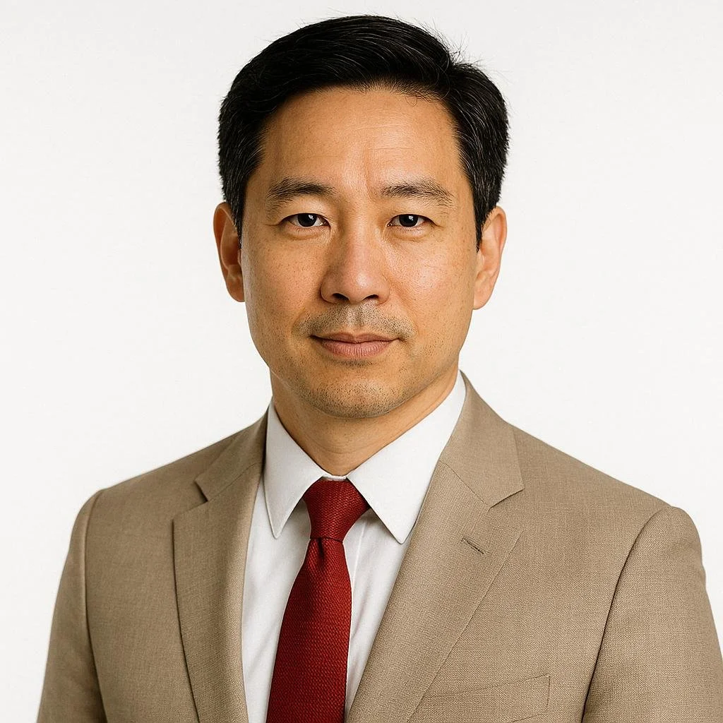 A woman with long curly hair in a high ponytail, wearing a red dress, hoop earrings, a necklace, and a subtle smile, facing slightly to the right against a white background.