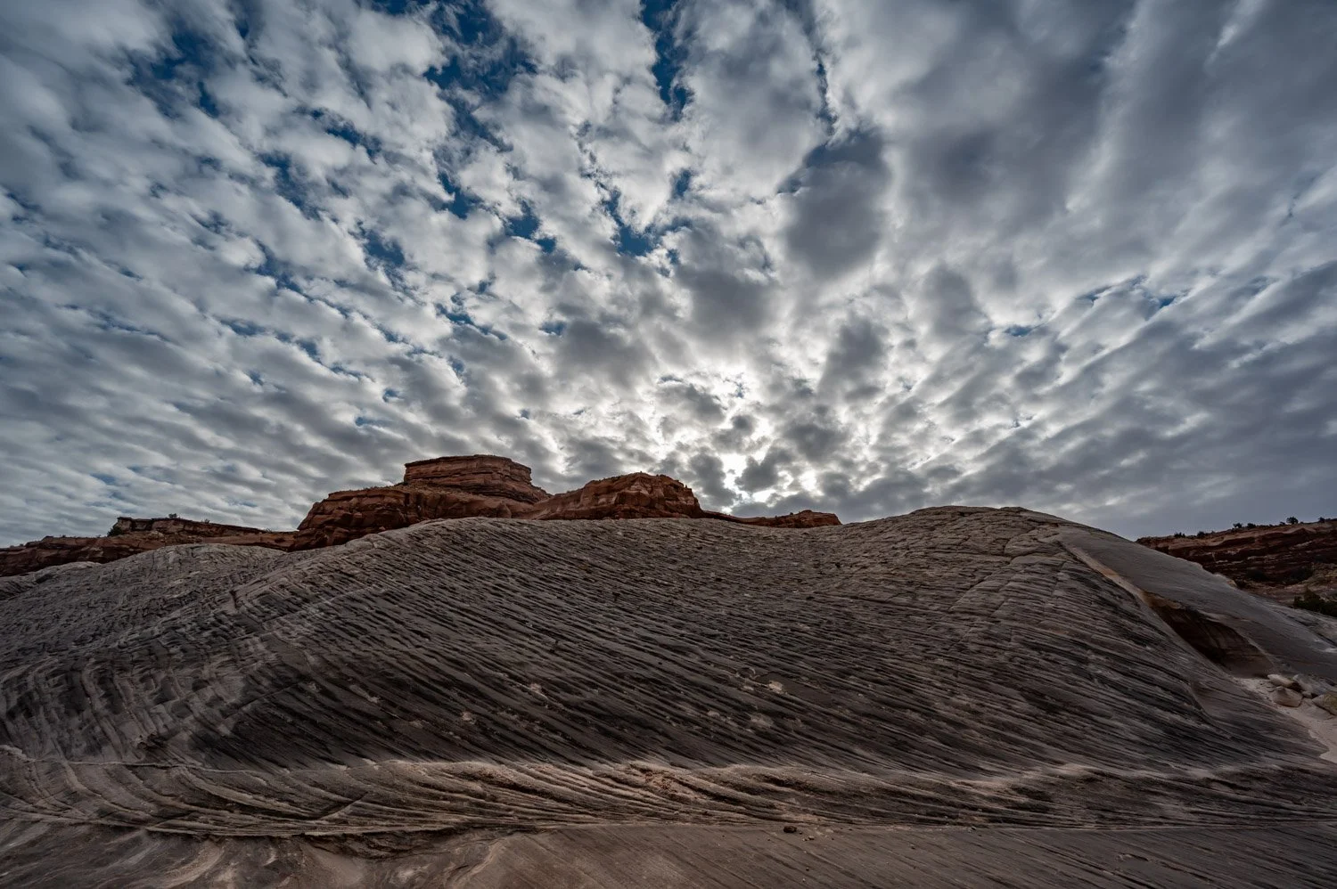 Rock formations under a cloudy sky in a desert landscape.
