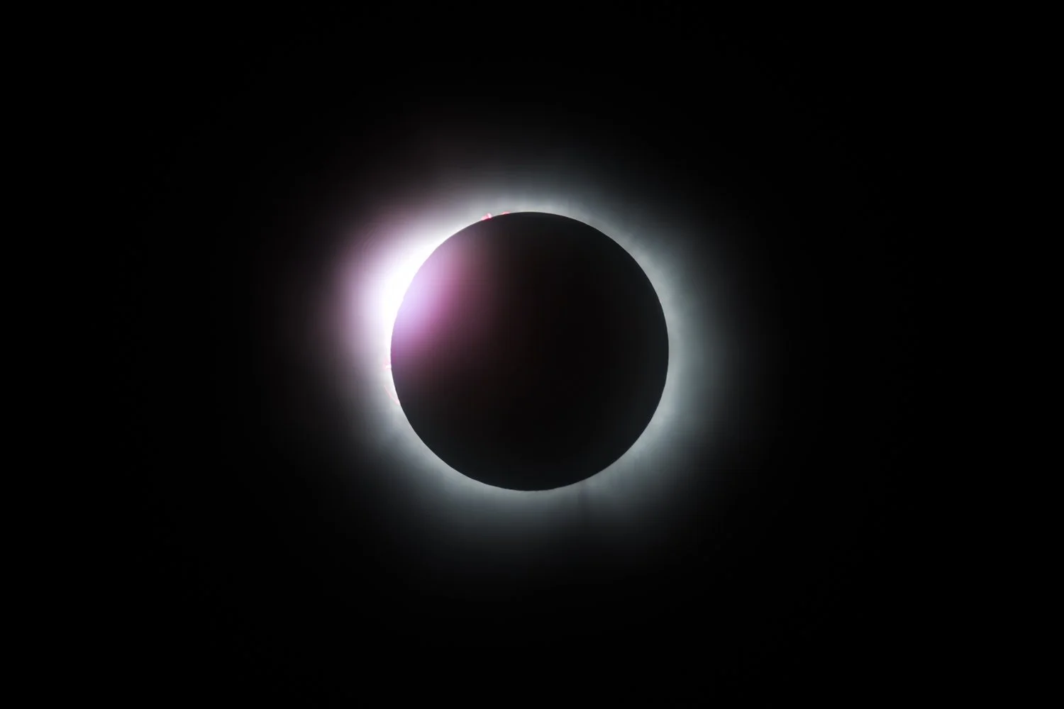A solar eclipse showing the moon covering the sun, creating a dark circle with a bright solar corona around it.