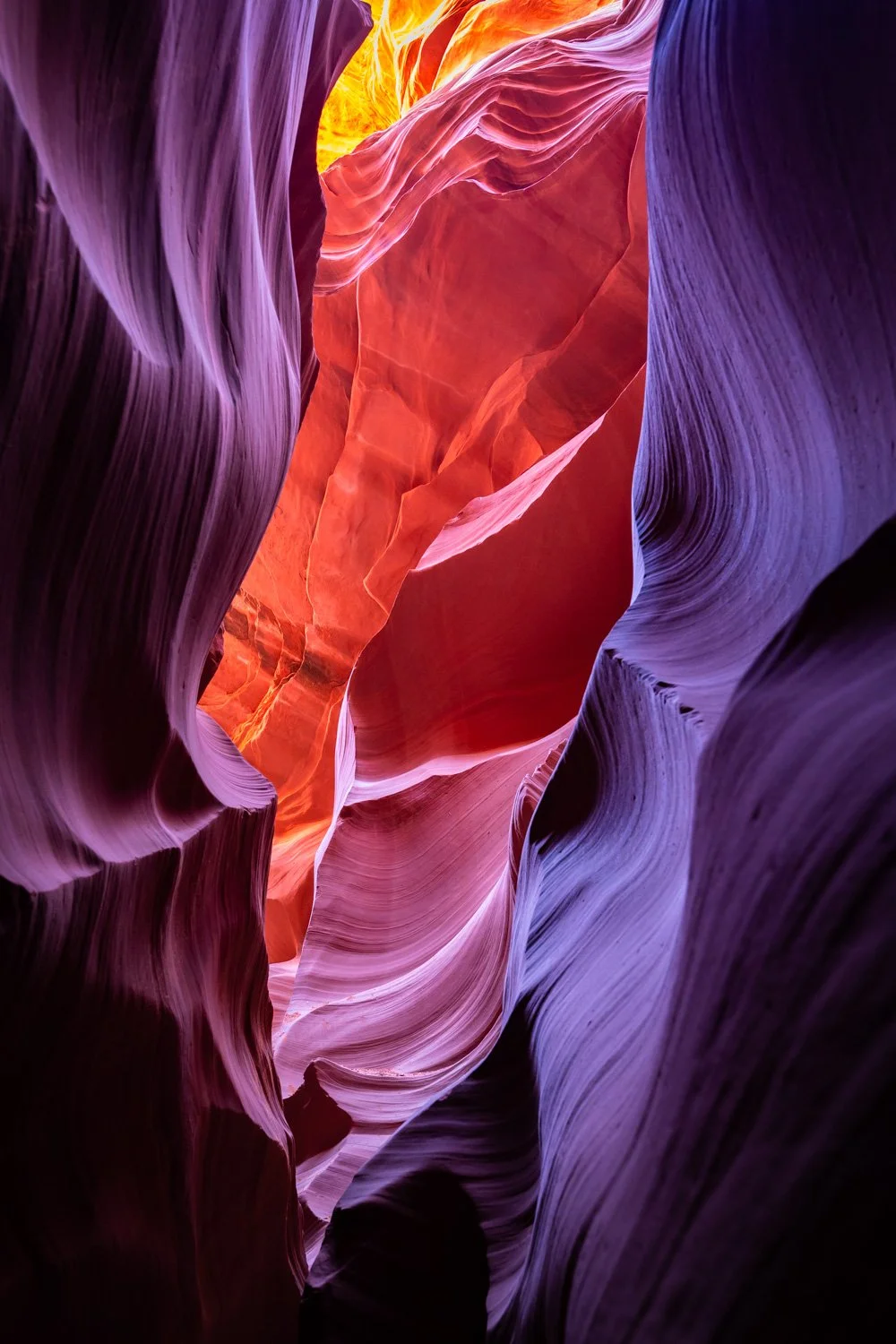 Colorful sandstone canyon with smooth, wavy walls in shades of purple, pink, and orange.