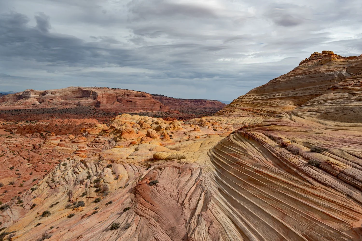 Colorful layered sandstone rock formations in a desert landscape under cloudy sky