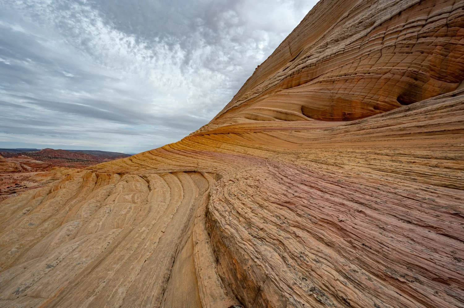 Layered colorful rock formations in a desert landscape with cloudy sky.