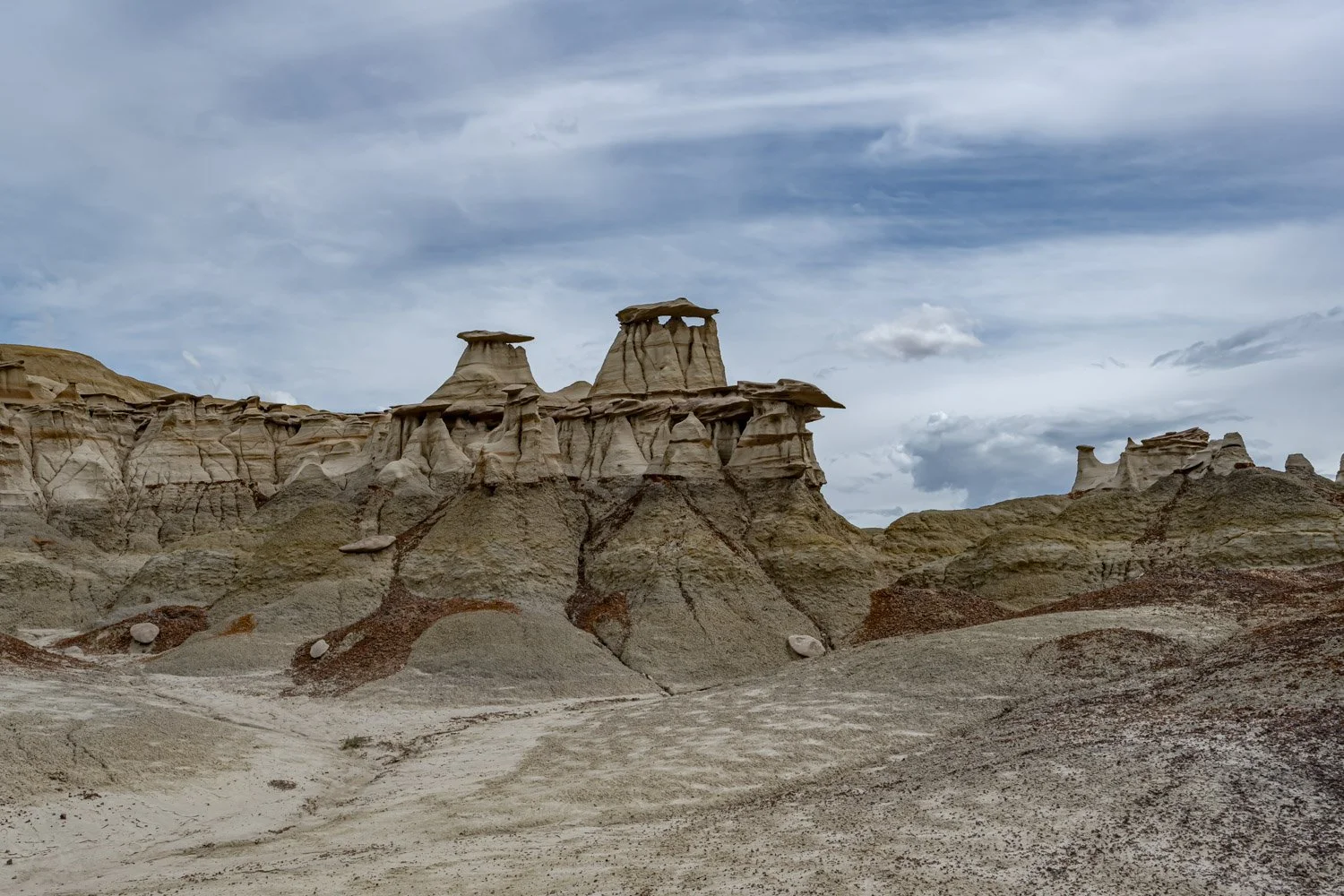 A desert landscape with unique rock formations under a cloudy sky.