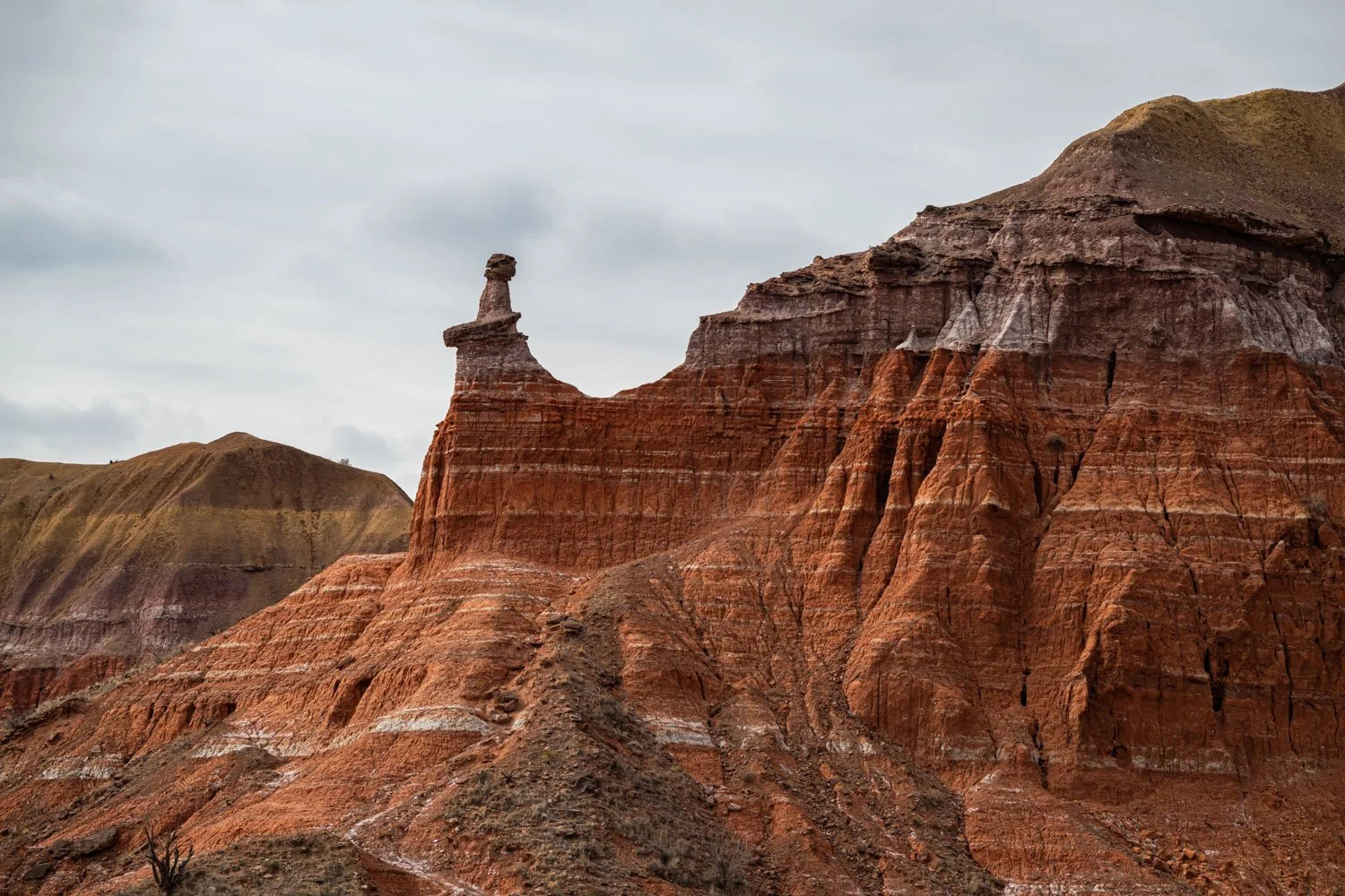Colorful, layered rock formations in a desert landscape with a cloudy sky.