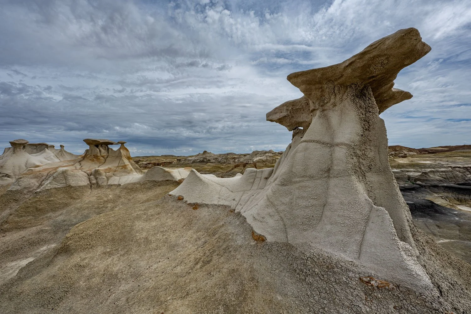 Unique rock formations in a desert landscape under a cloudy sky.