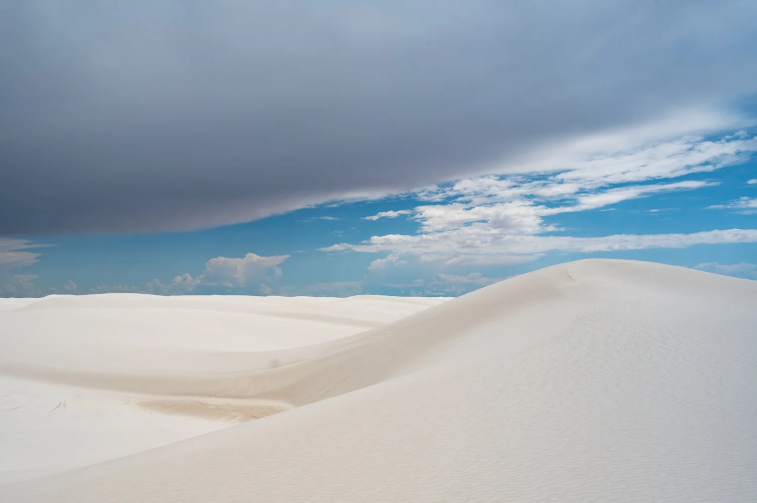 White sand dunes under a partly cloudy sky.