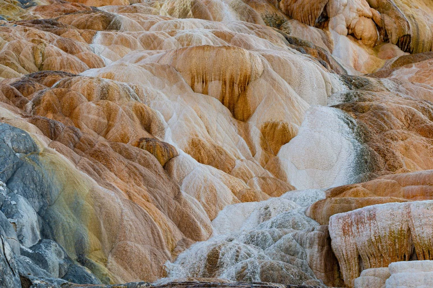 Colorful mineral deposits forming layered rocks with white and reddish-brown hues, possibly from a geothermal or mineral-rich area.