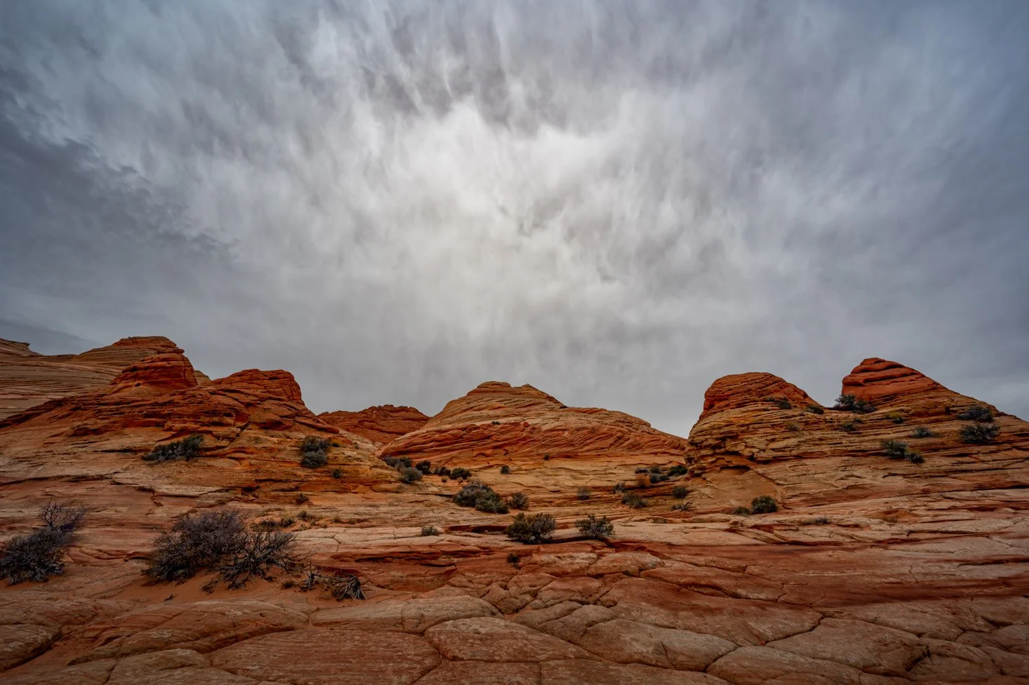 Red sandstone rock formations under a cloudy sky in a desert landscape.