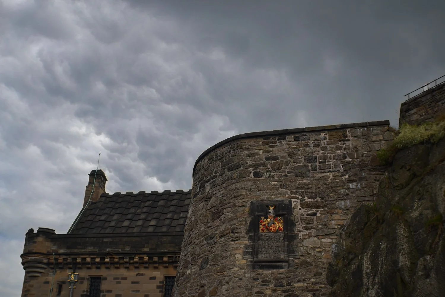 A historic stone castle with a plaque, under a cloudy sky.