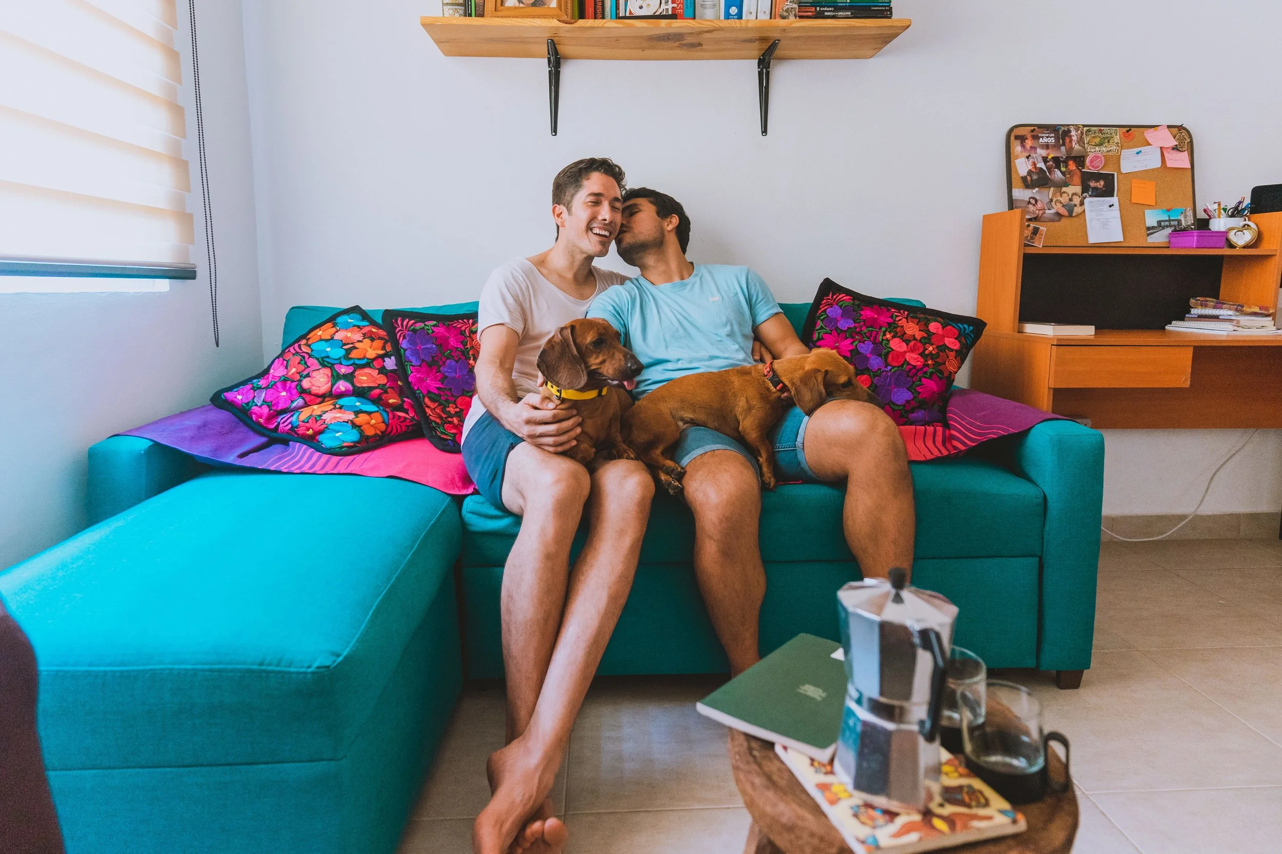 Two partners sitting closely together on a couch with their dogs, sharing an affectionate moment, reflecting the connection couples can build through Couples Therapy Massachusetts.