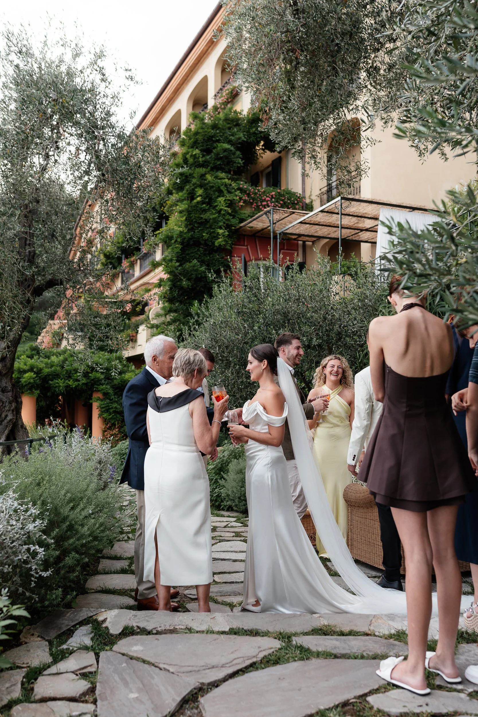 Wedding celebration outdoors on stone path surrounded by greenery; Belmond Splendio Portofino wedding at sunset, taken by destination wedding photographer weddings by Emma Olivia with an editorial, documentary approach.