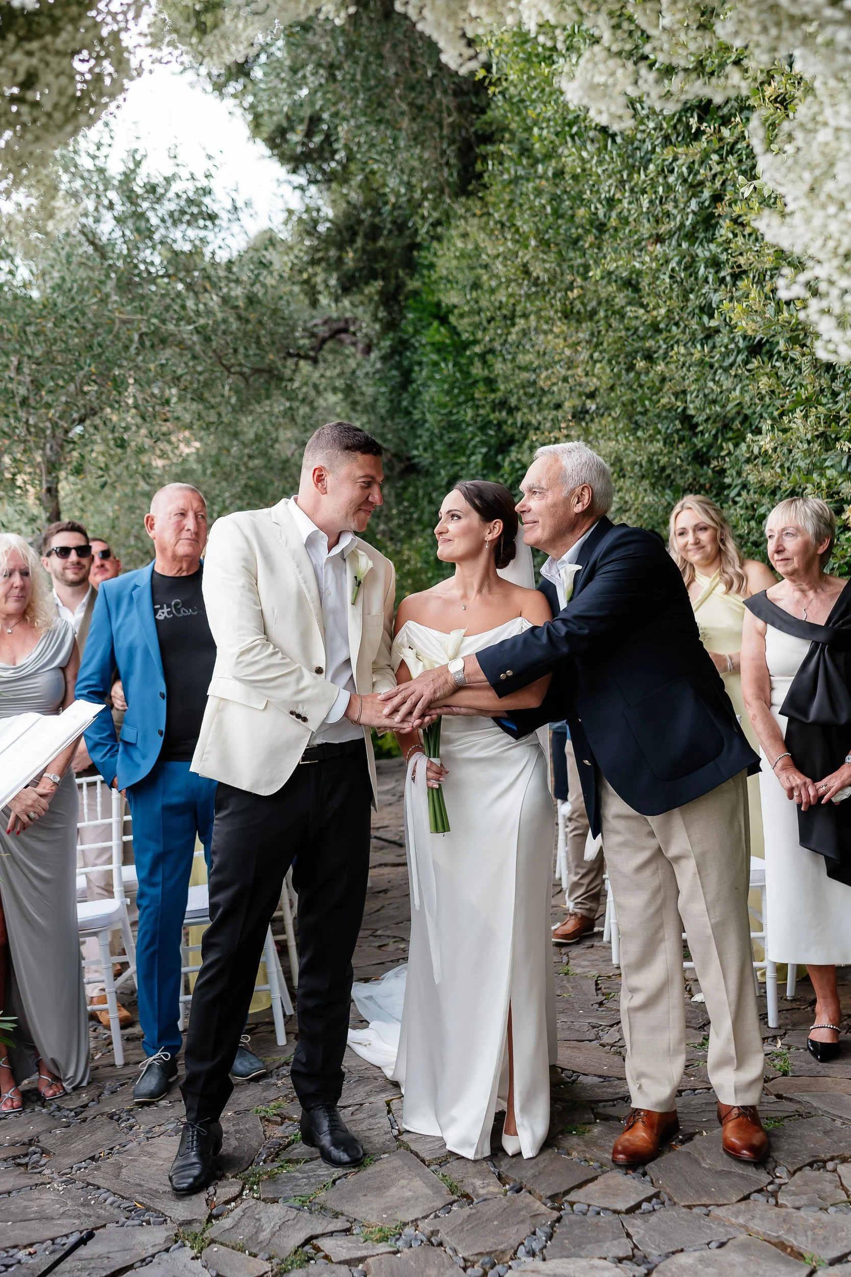 Wedding ceremony with the bride, groom, and father of the bride holding hands and smiling. overlooking Portofino at a Belmond Splendido Wedding, Portofino Italy. Photos taken by editorial destination wedding photographer Weddings by Emma Olivia. 