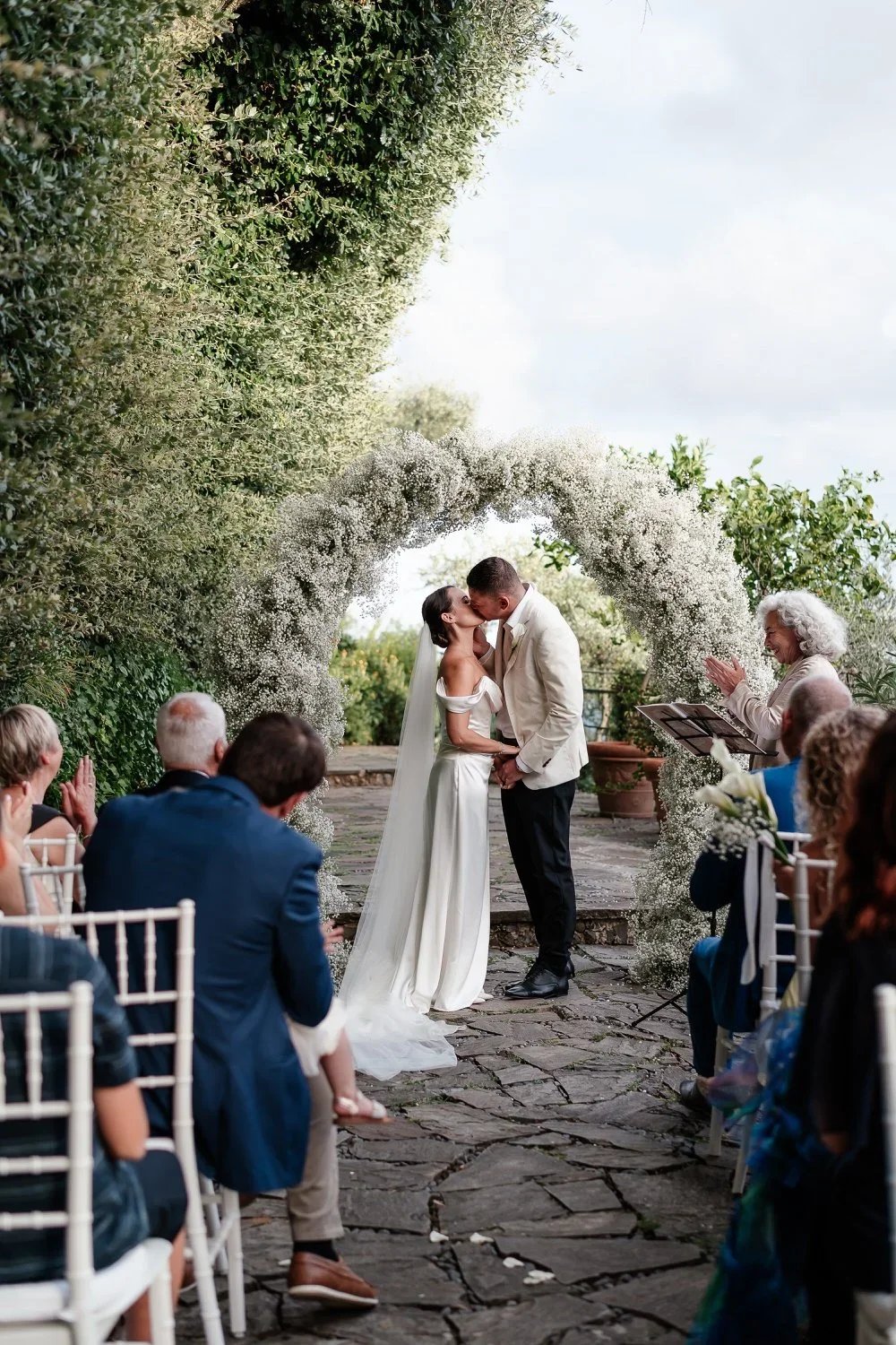bride and groom getting married on the terrace gardens at Belmond Splendido in Portofino Italy. They are surrounded by gypsophila and all of their loved ones in an intimate ceremony