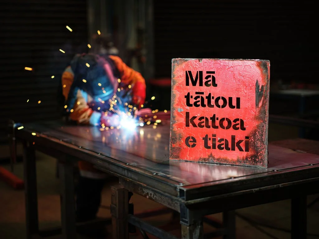 Person welding behing WM Waste Management tagline cut out of metal