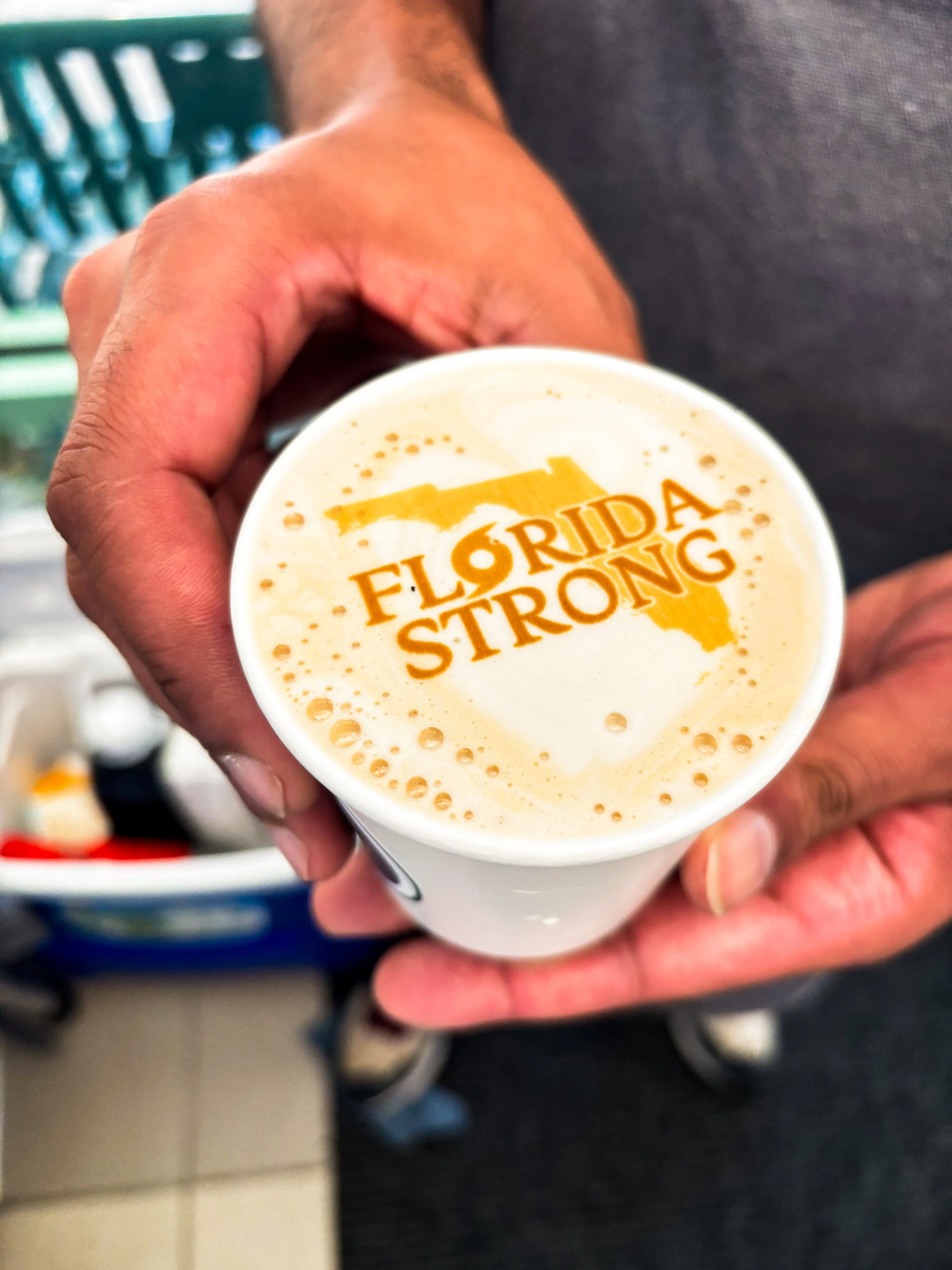 A person holding a coffee cup with the words 'Florida Strong' and a graphic of Florida written in orange on the foam.