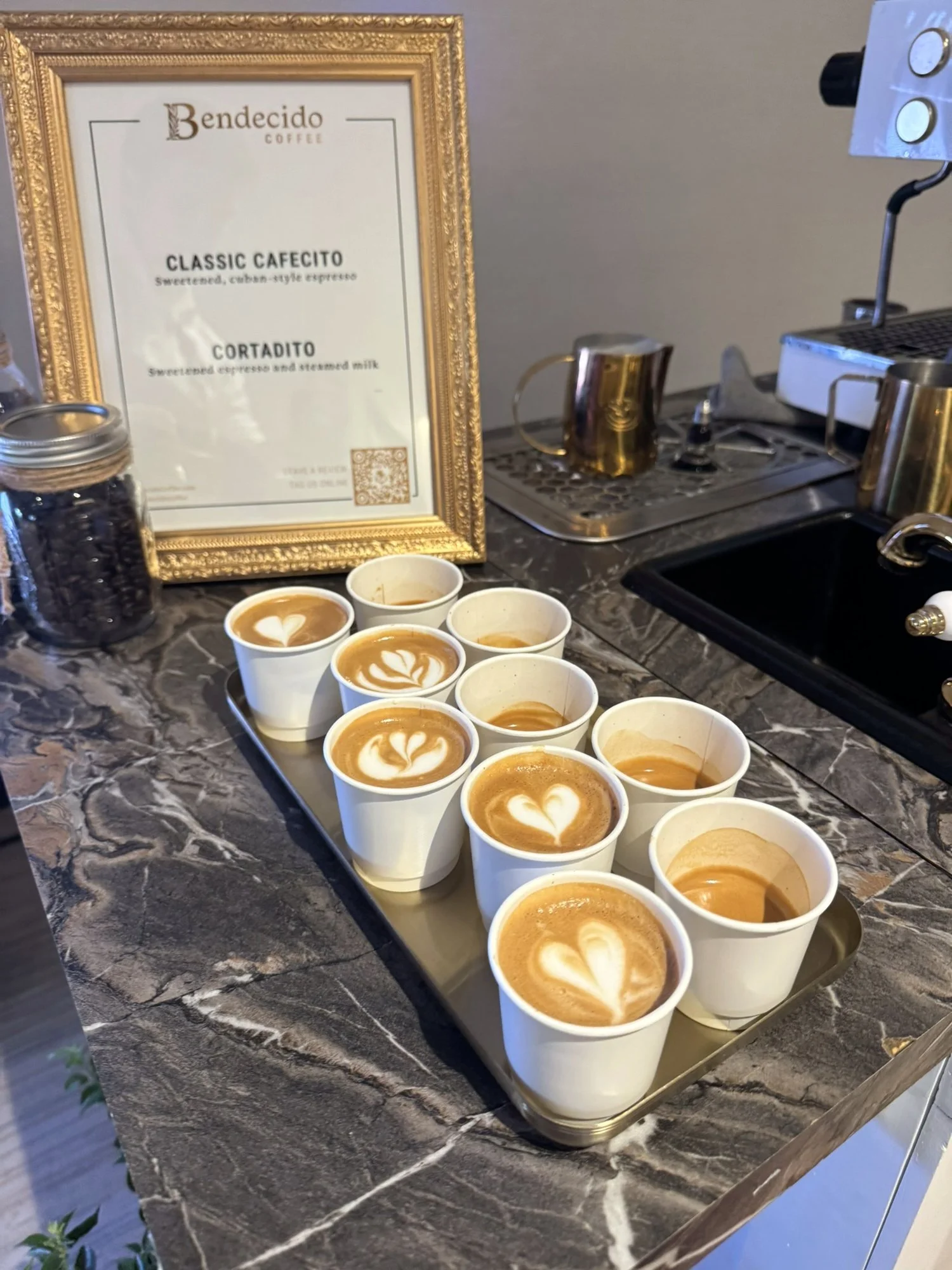 Tray of lattes with foam art next to the Bendecido Coffee drink menu
