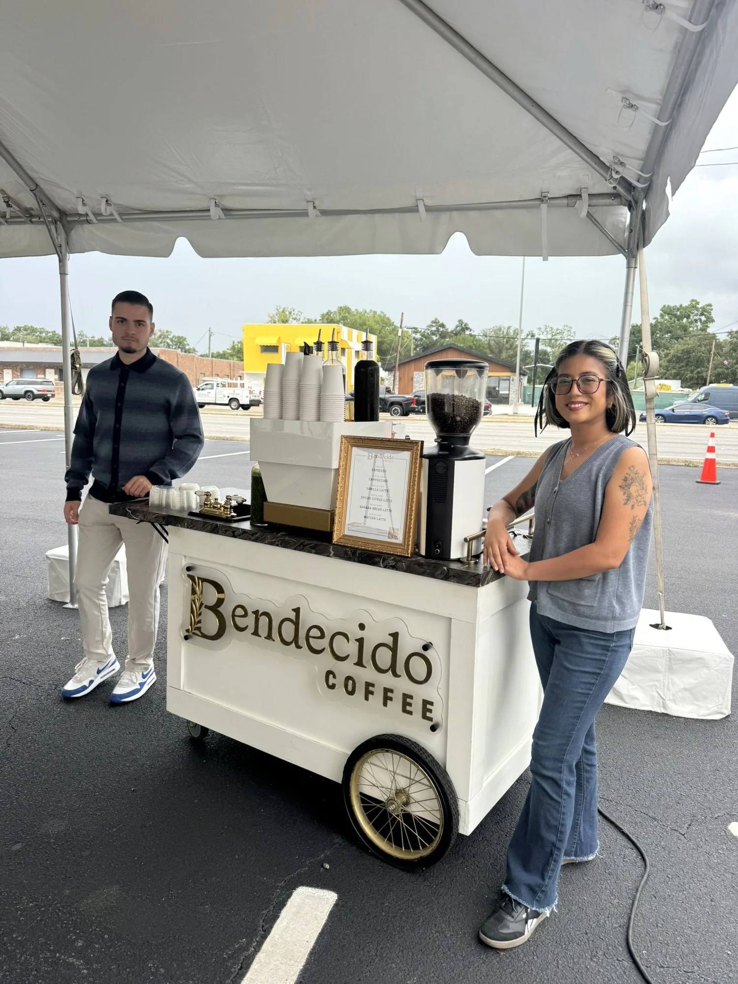 Two baristas with the Bendecido Coffee cart under a tent at an outdoor Tampa Bay event