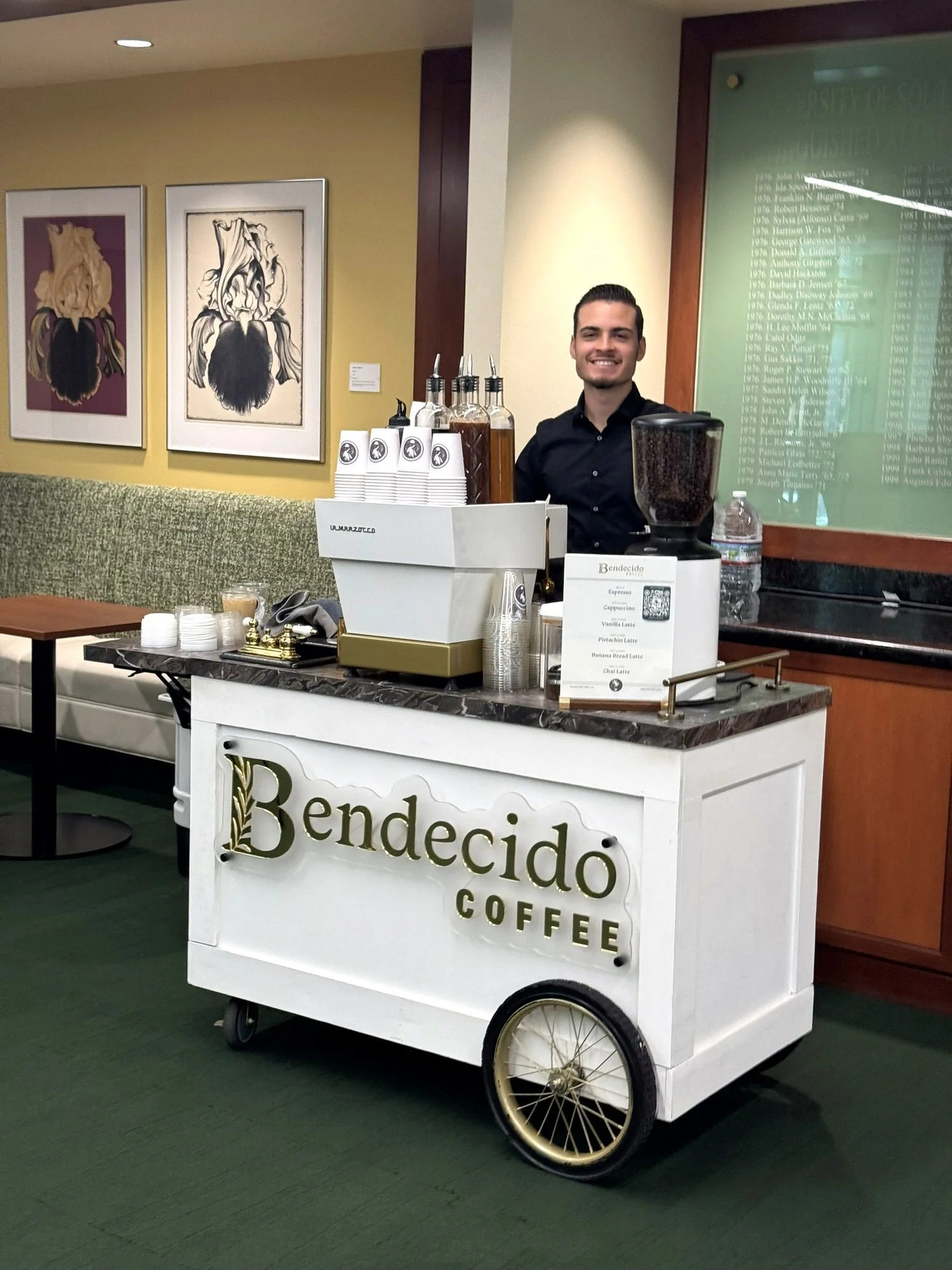 Smiling barista at the Bendecido Coffee cart in a university lounge in New Tampa