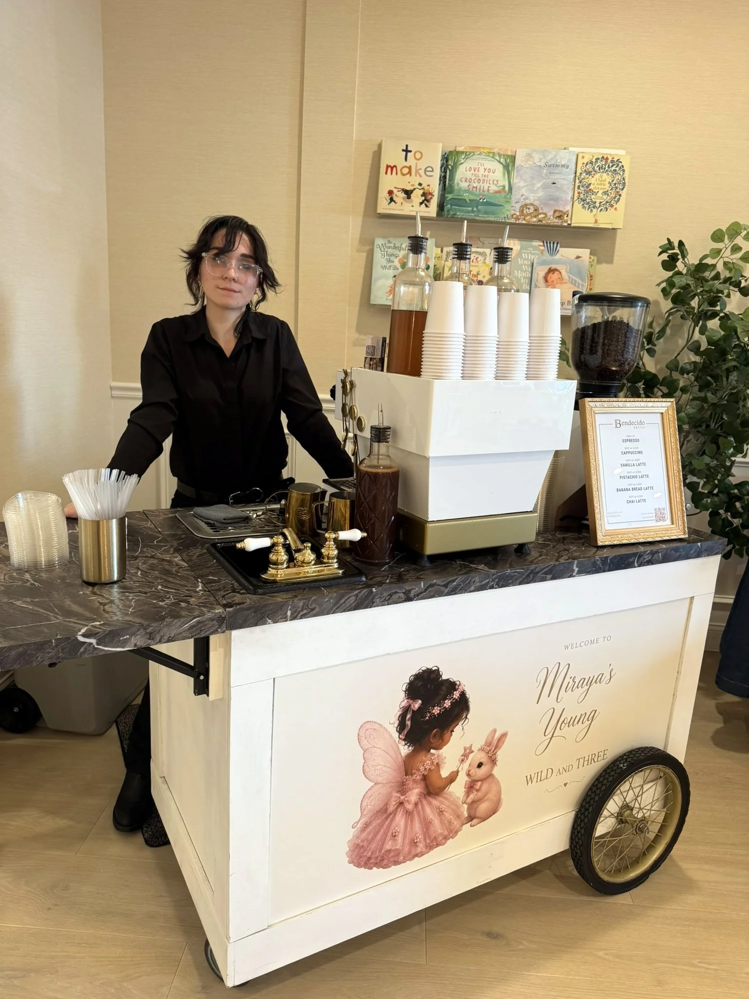 Barista at a Bendecido Coffee cart with a custom baby shower design at a Tampa Bay celebration