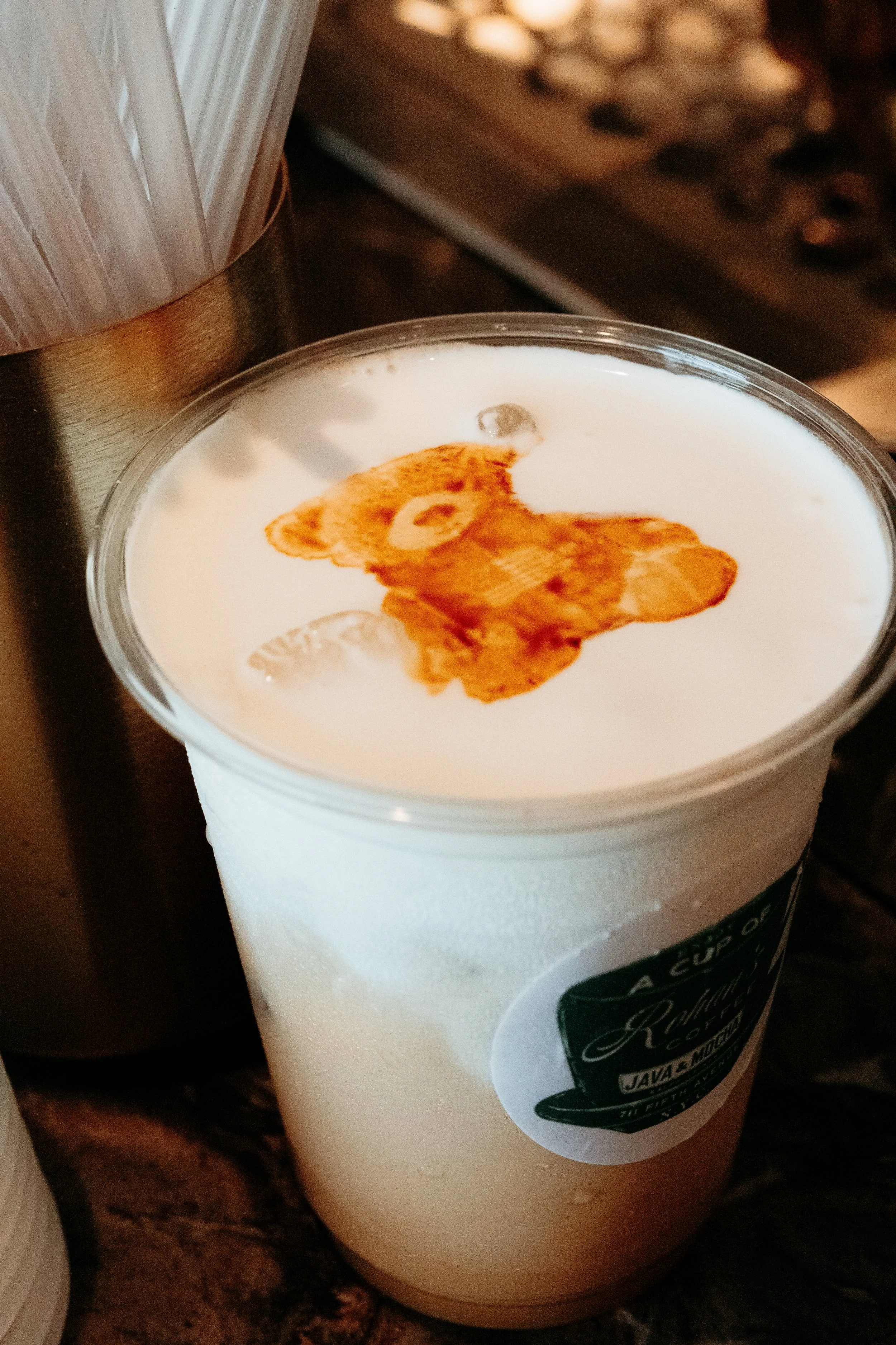 A Bendecido Coffee iced cup filled with a latte topped with cold foam and a bear-shaped latte art design.