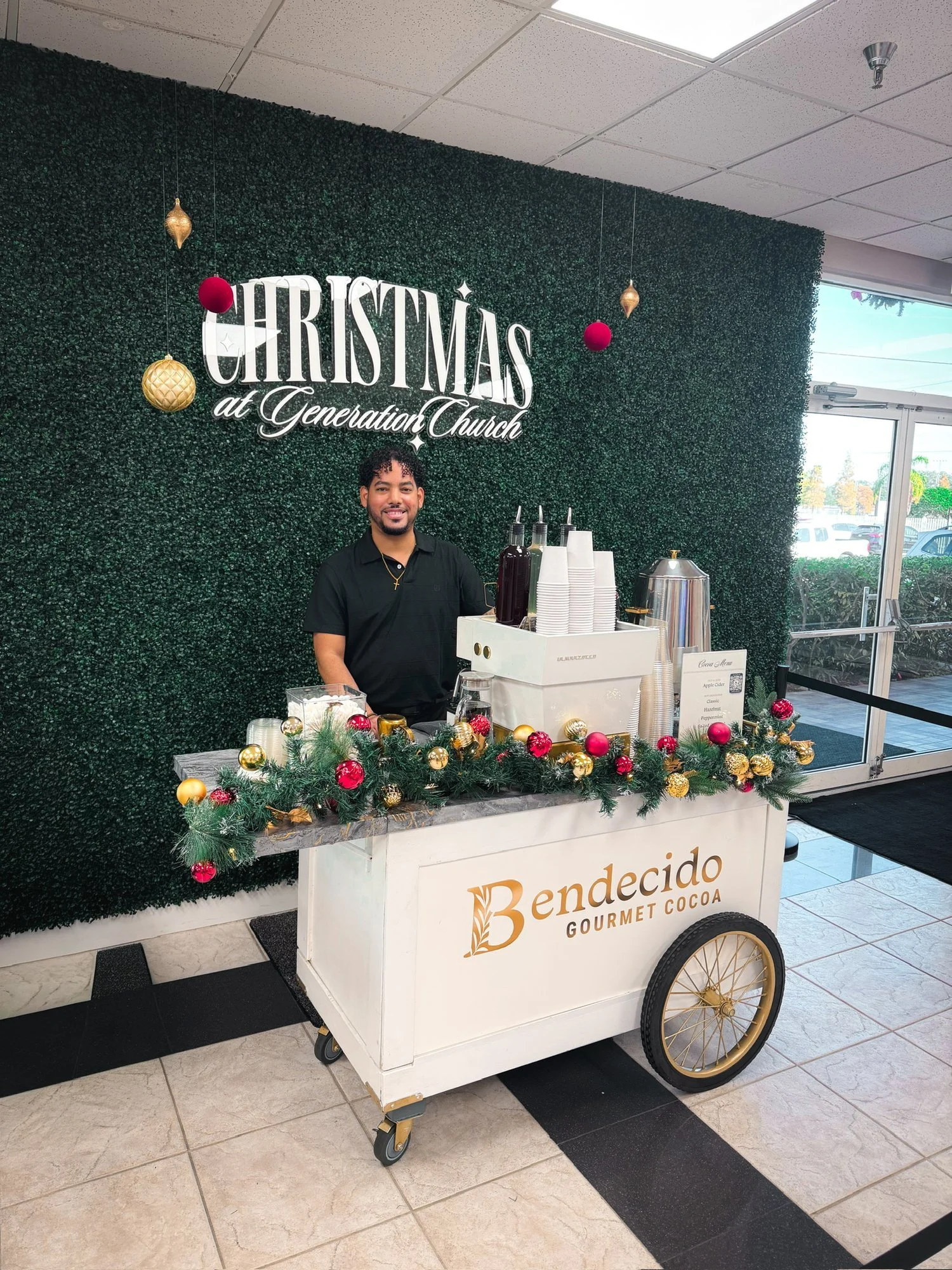 Barista behind the Bendecido Coffee cart decorated with garland at a Christmas church event in Tampa Bay