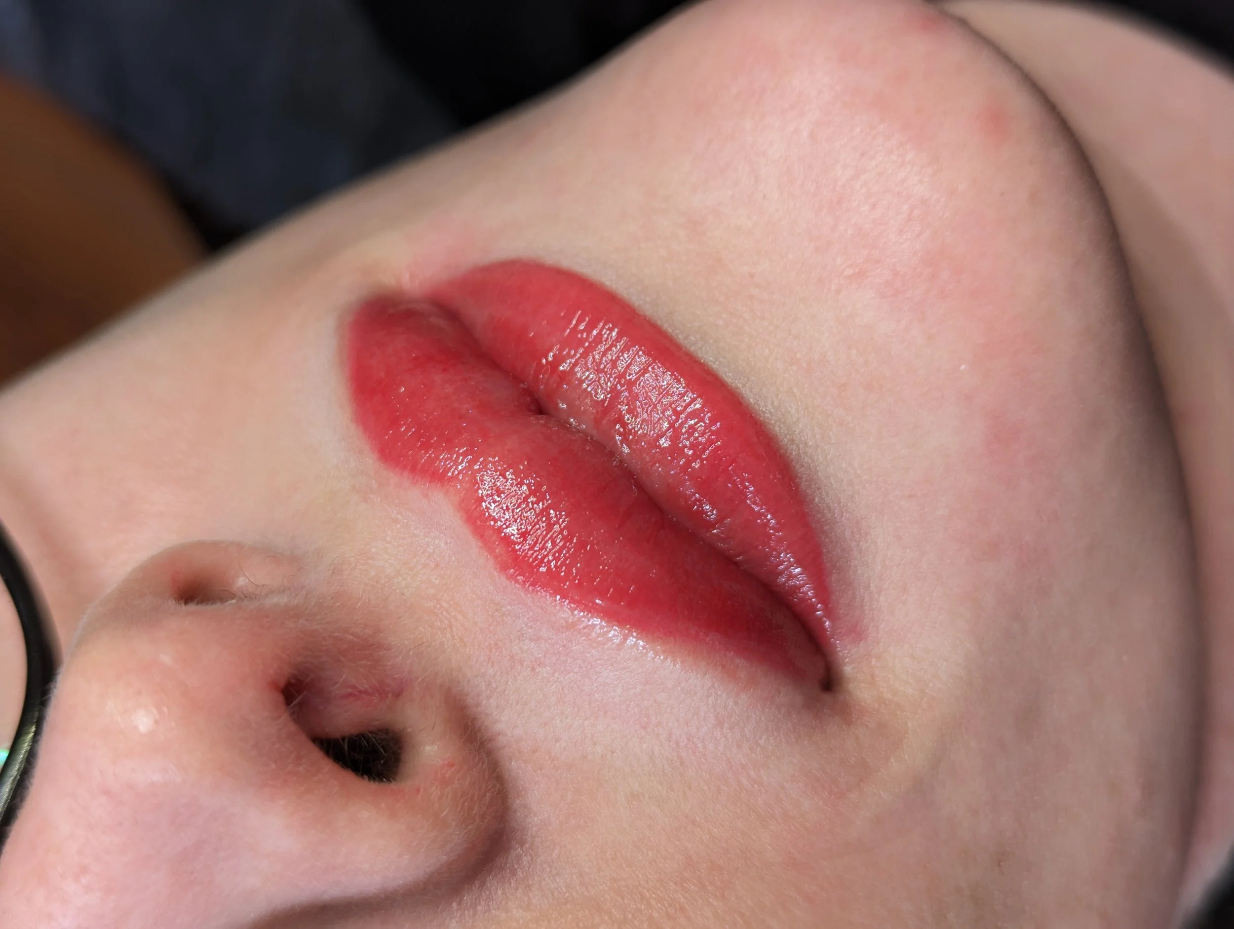 Close-up of a person's face with red lipstick, lip blush tattoo permanent makeup by honeypot lashes.
