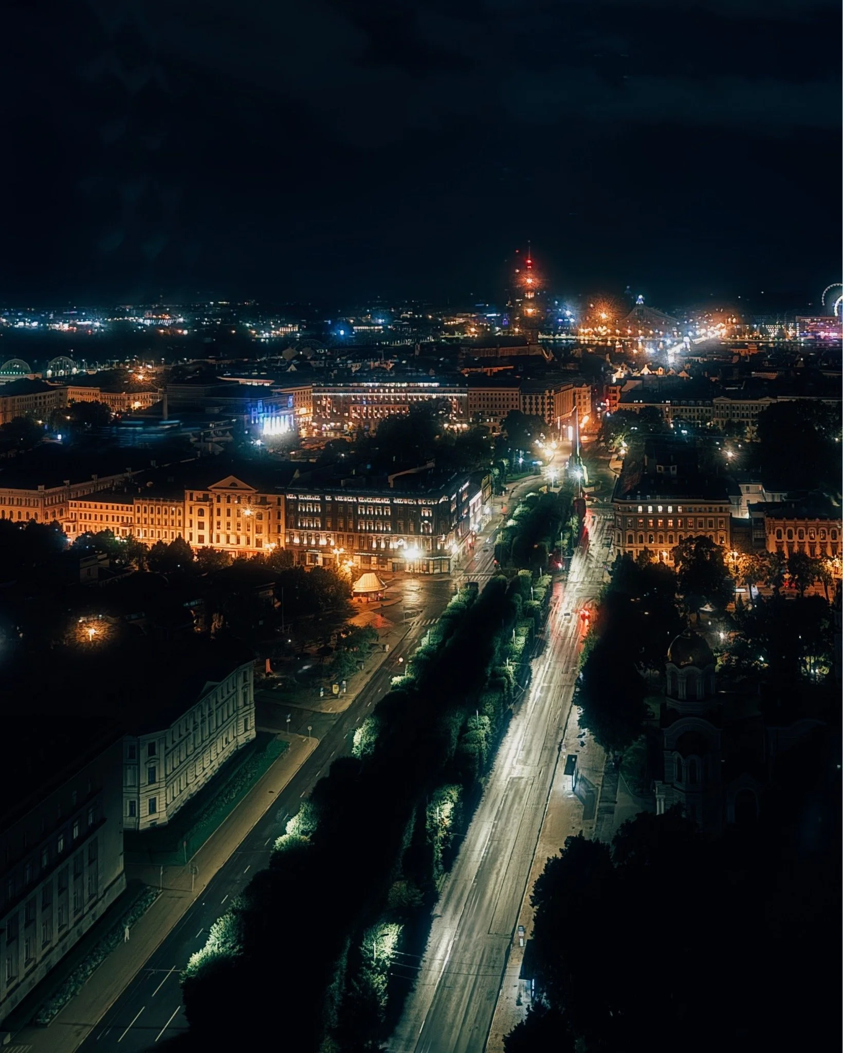 Nighttime cityscape with illuminated buildings, streets, and a dark sky.