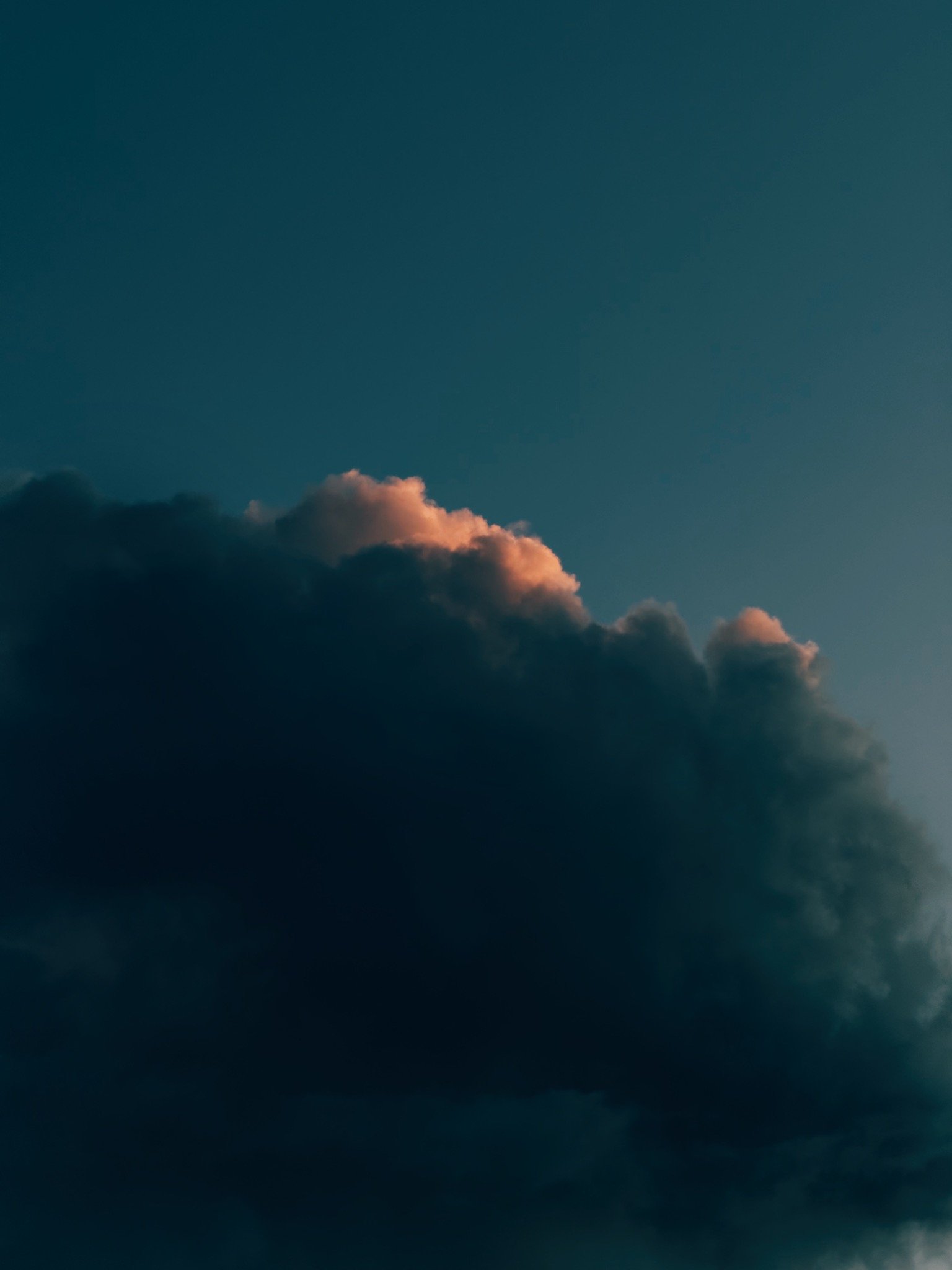 Dark clouds in the sky with a hint of sunlight illuminating the edges of some clouds.