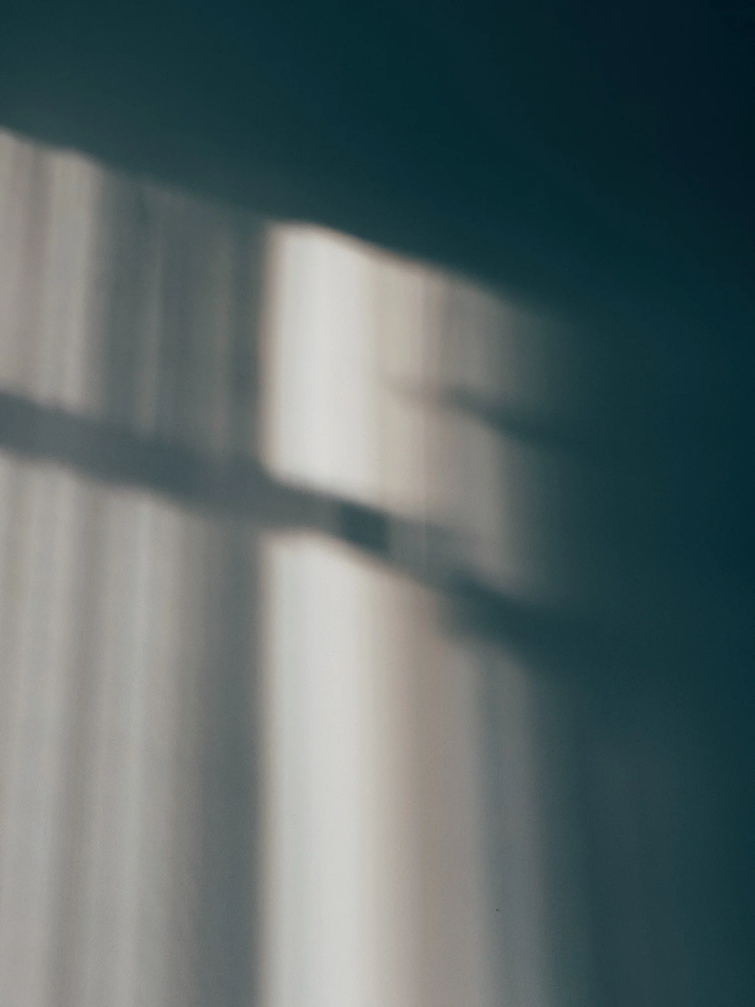 Blurred image of sunlight casting shadows through a window onto a wall.