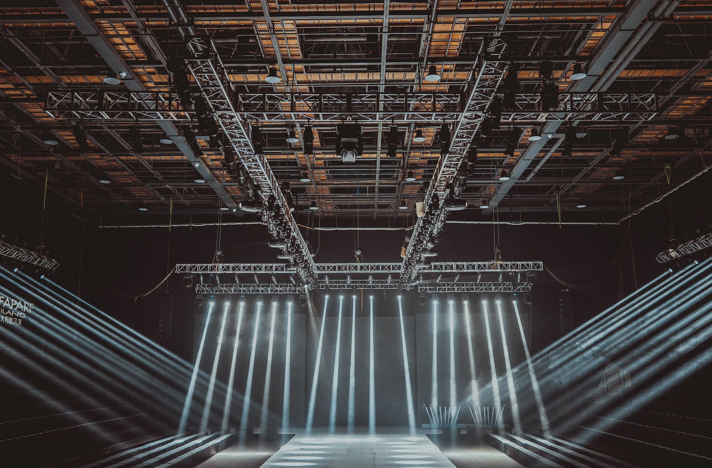 Empty stage with bright lights and a high ceiling with rigging for lighting and stage equipment.
