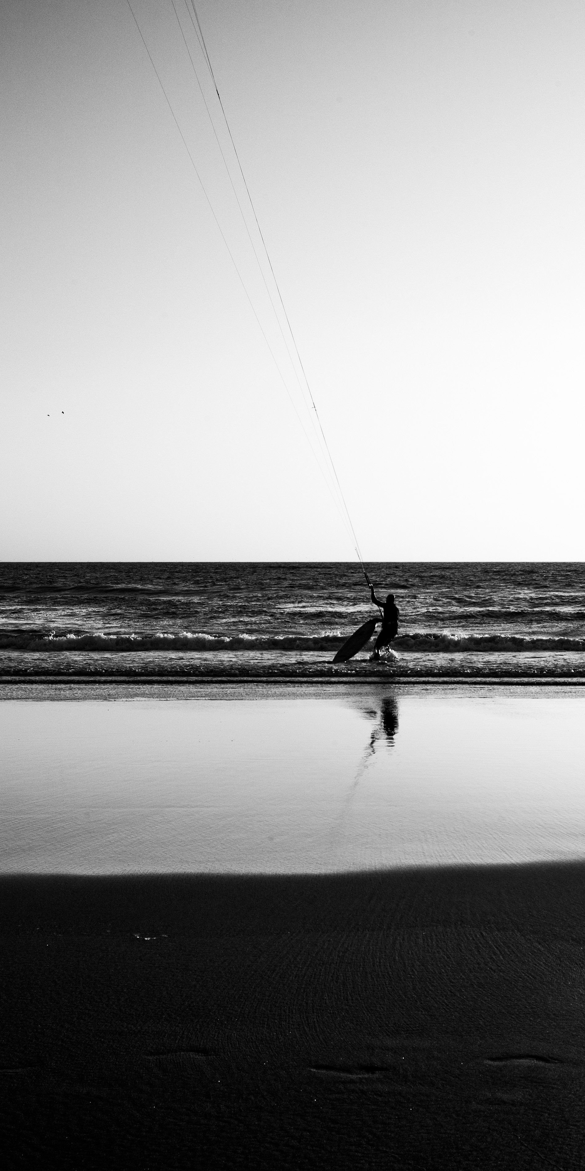 A wind surfer pulls in back to land, hauling in their sail one evening in a 2022 summer