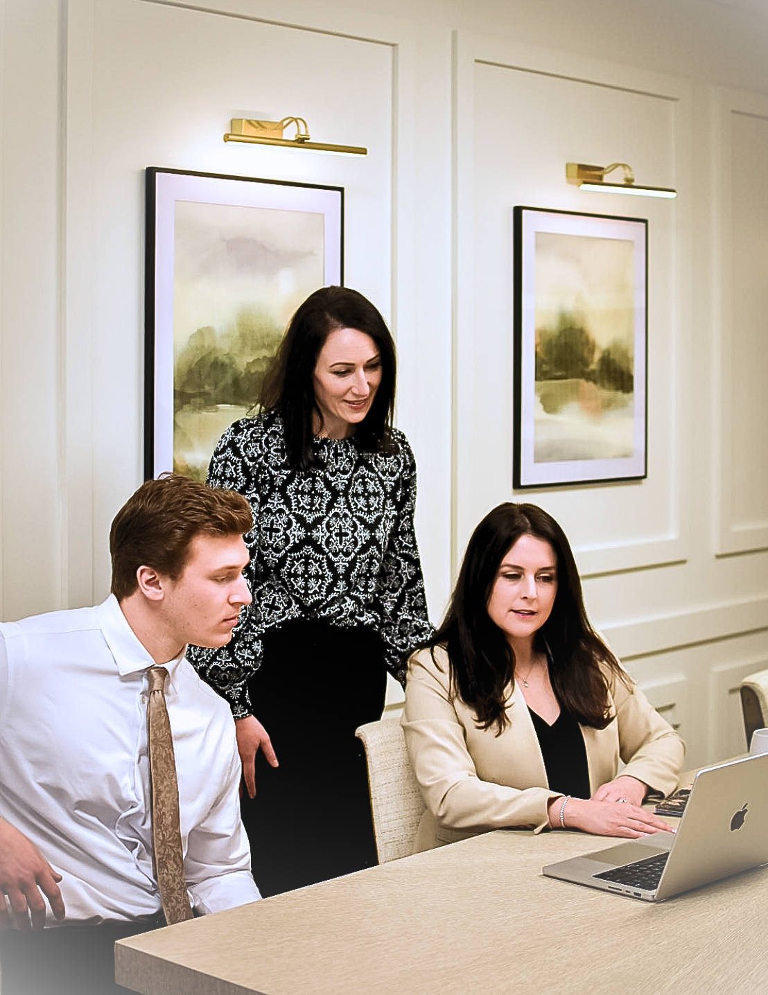 Scenic landscape of a large lake with green hills in the foreground and tall, rugged mountains in the background under a cloudy sky.