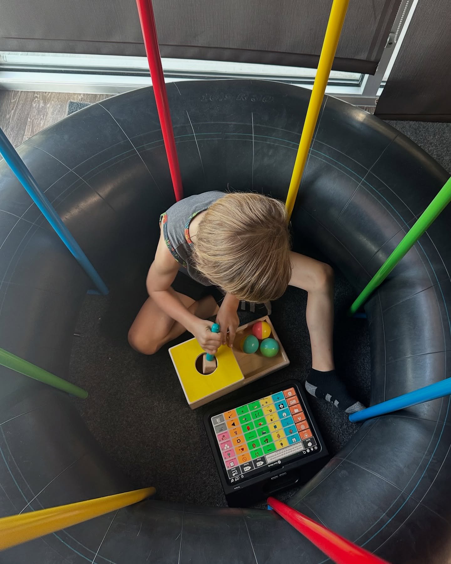 Trapped in a tire? Nope, just deep in play!
This kiddo’s building language and having a blast. With an AAC device by their side and a playful setup all around, we’re modeling core words like in, out, more, and go through hands-on fun. ✋