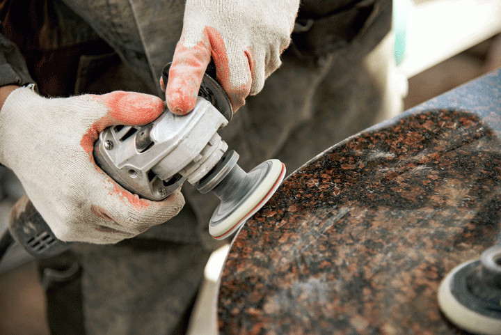 Specialist polishing a piece of granite with a hand polisher - Innovative Countertop Solutions