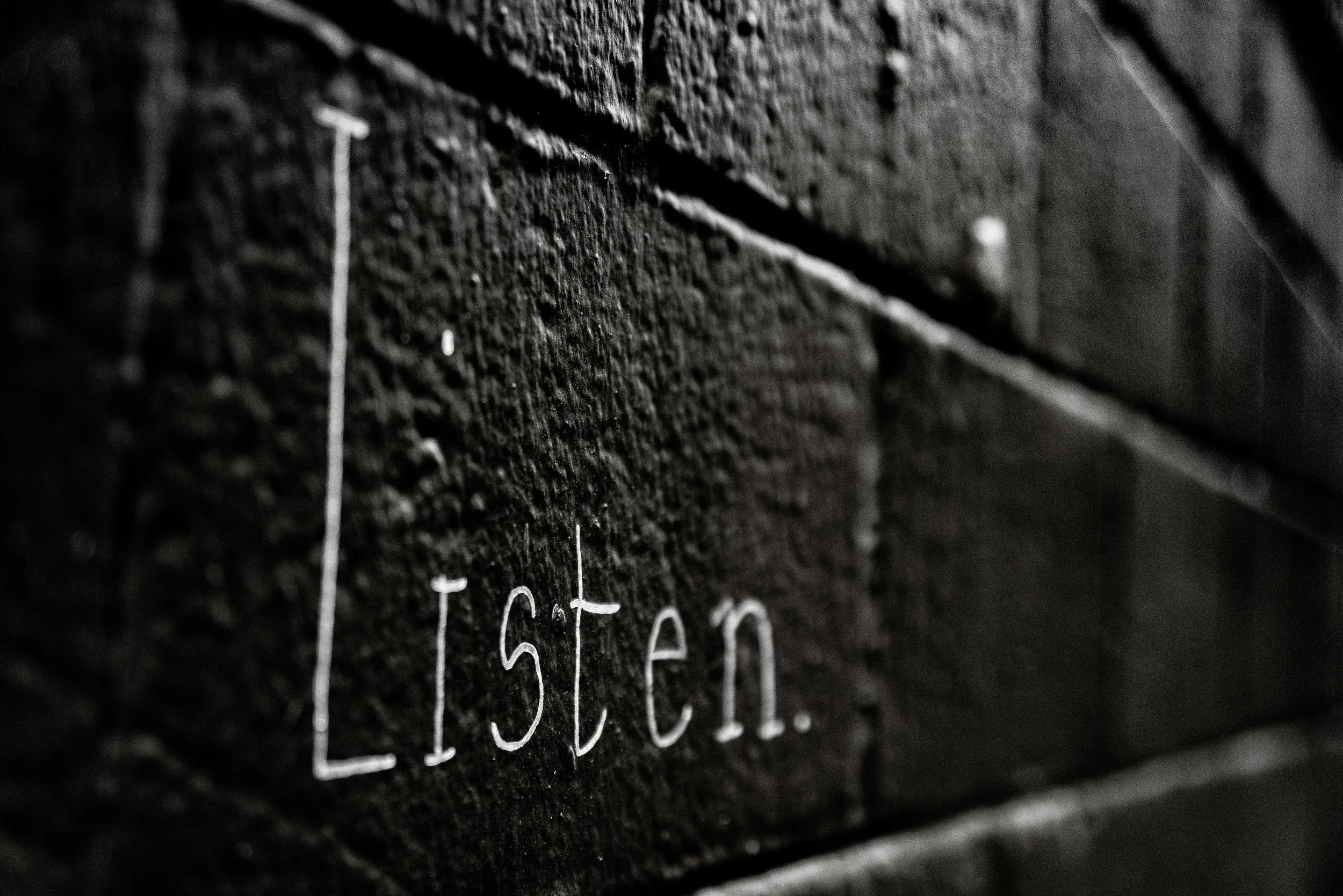 The word "listen" written on a brick wall
