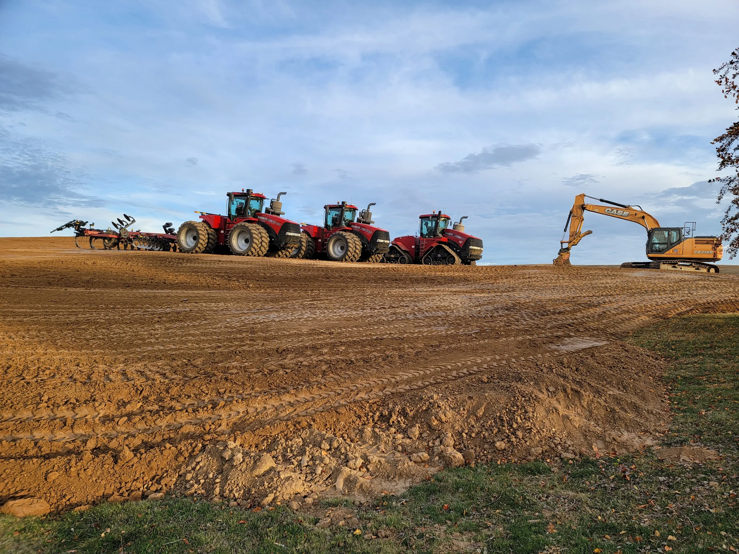 EXCO red tractors and earthmoving equipment lined up on a jobsite.
