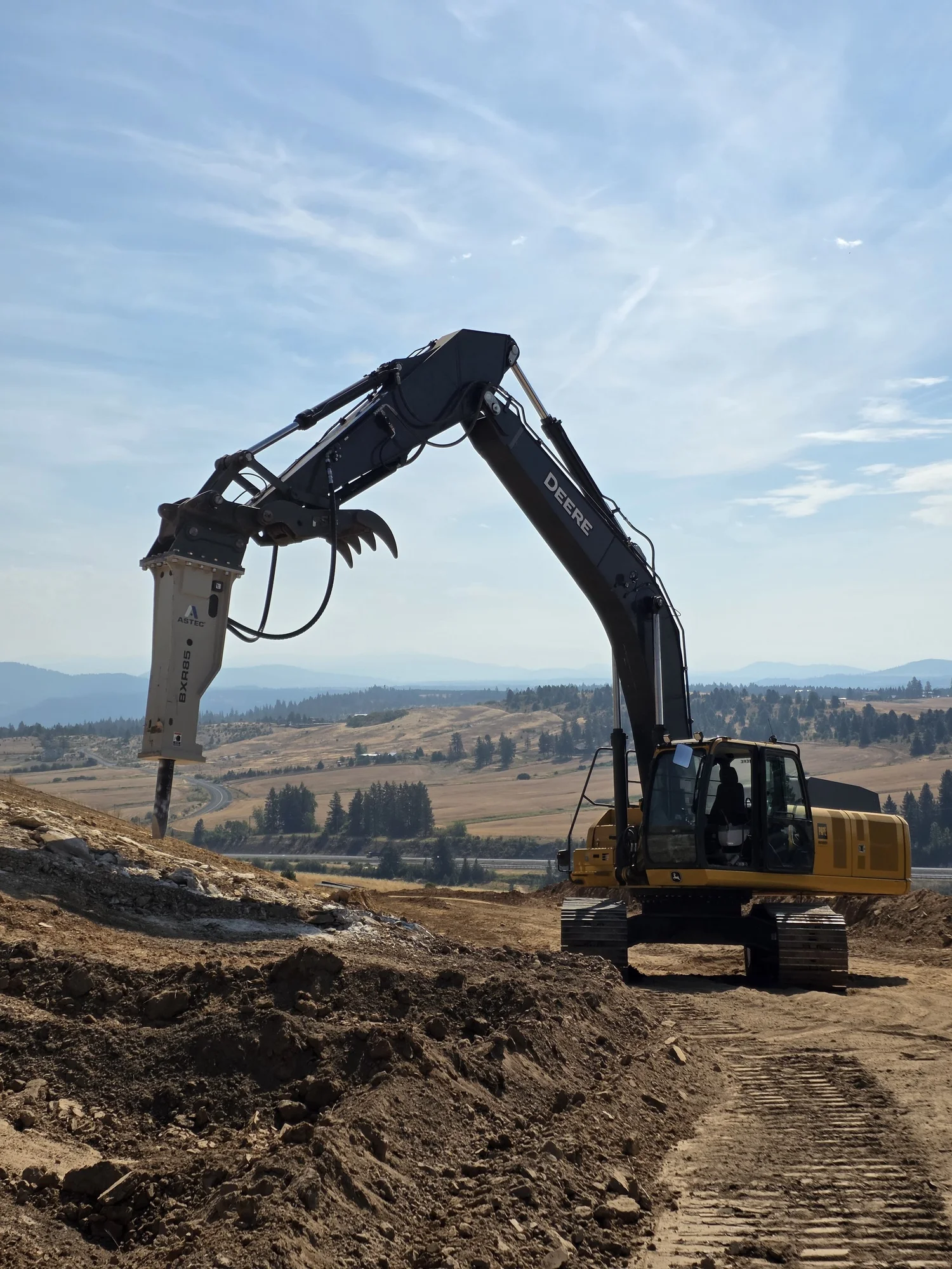 Full view of an EXCO excavator and breaker attachment on a hillside jobsite.