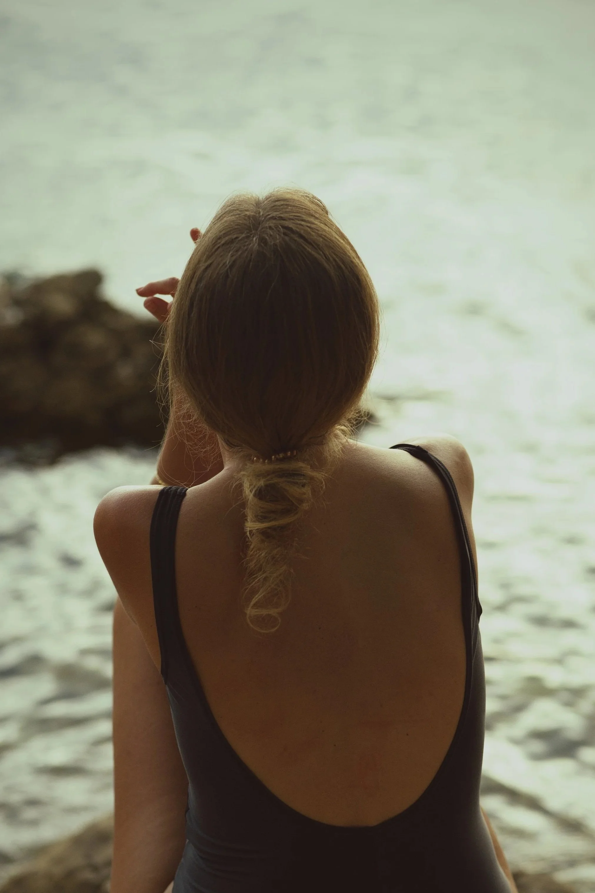 Woman standing quietly by the water in the evening light.