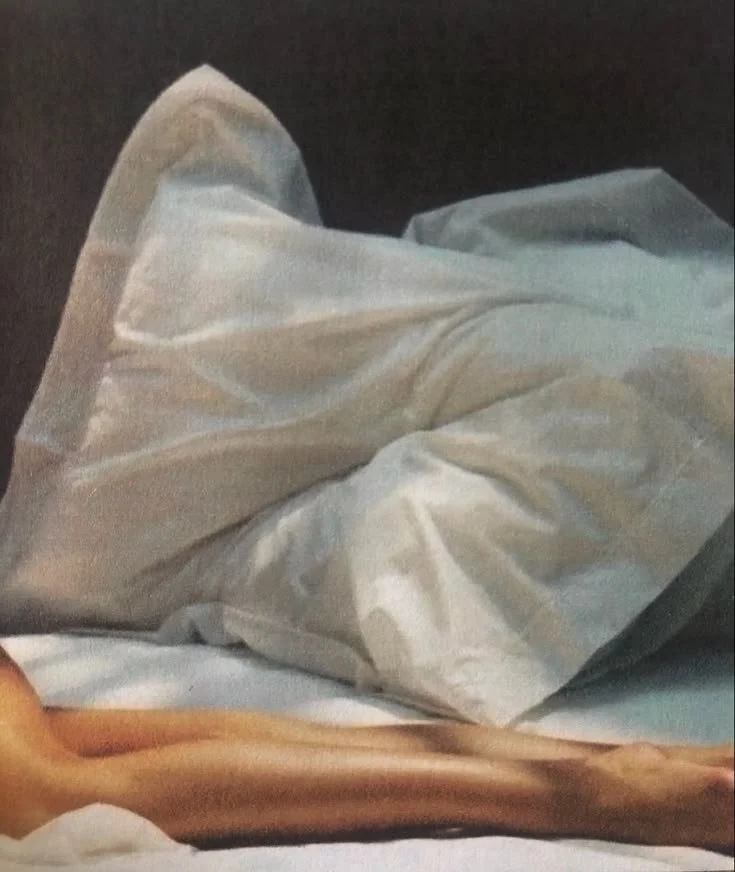Close-up of a person lying in bed with a white crumpled sheet or blanket covering part of their body.