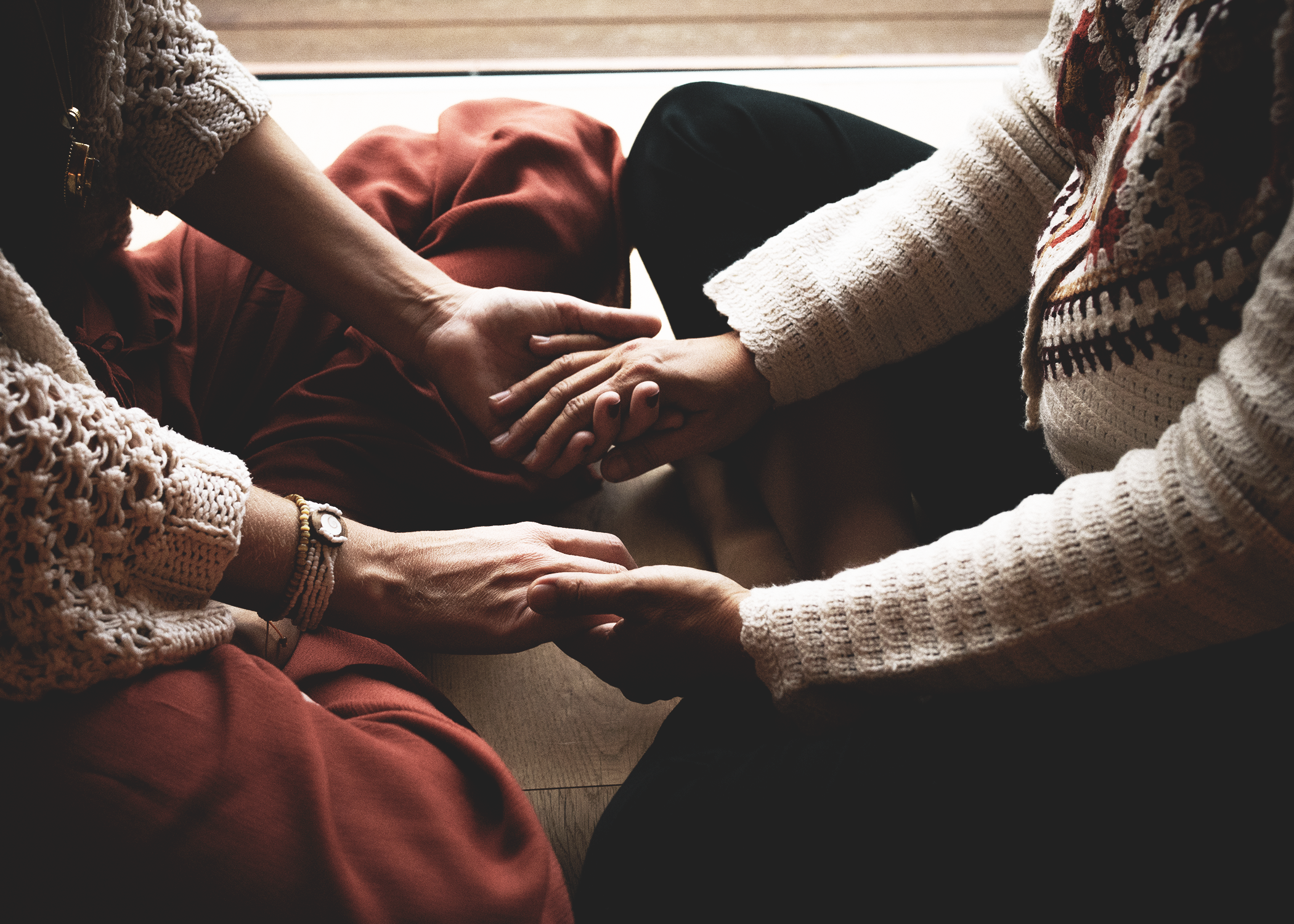 Intimate gathering of women around a candlelit table in nature.
