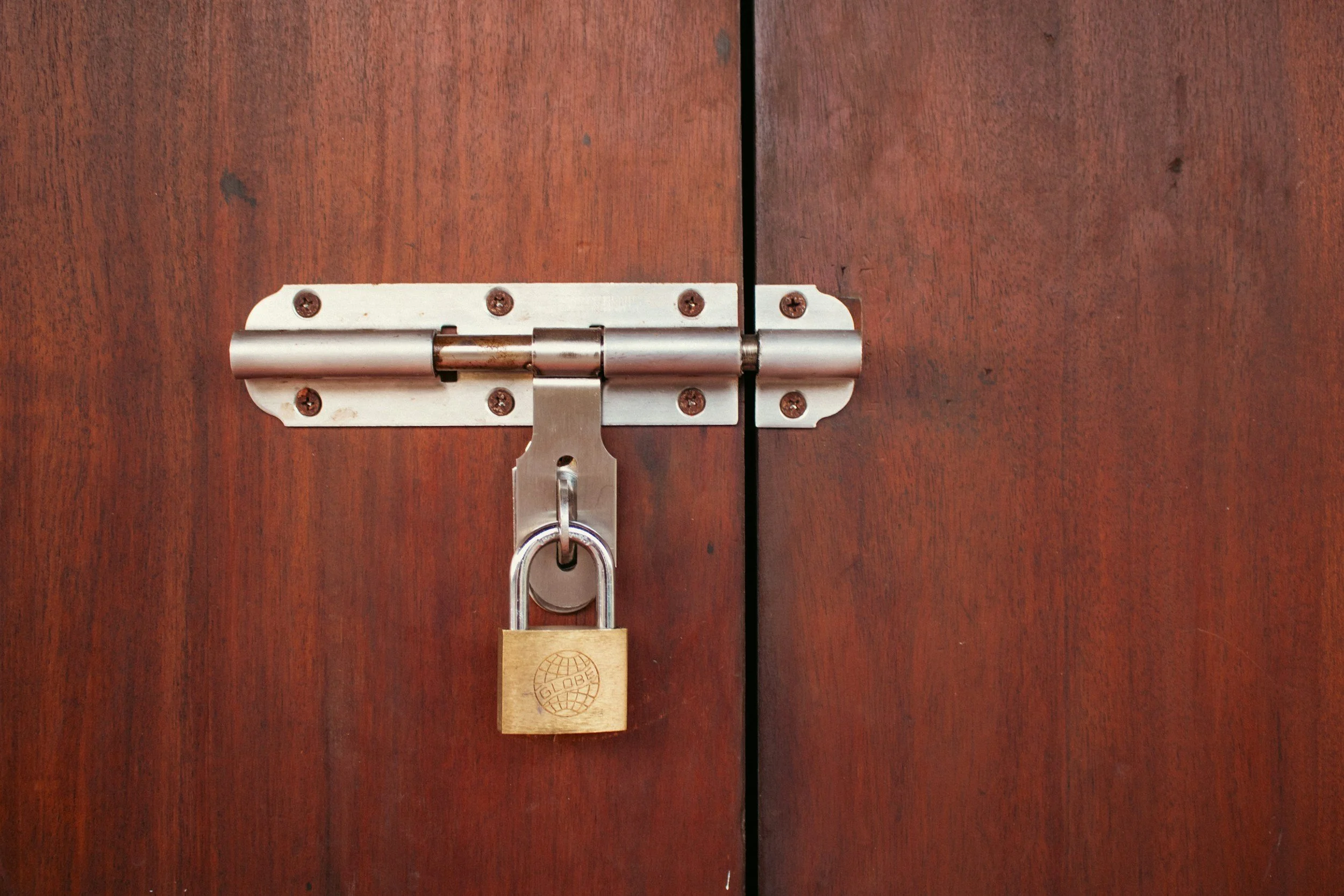 A wooden door with a metal hinge and a padlock.