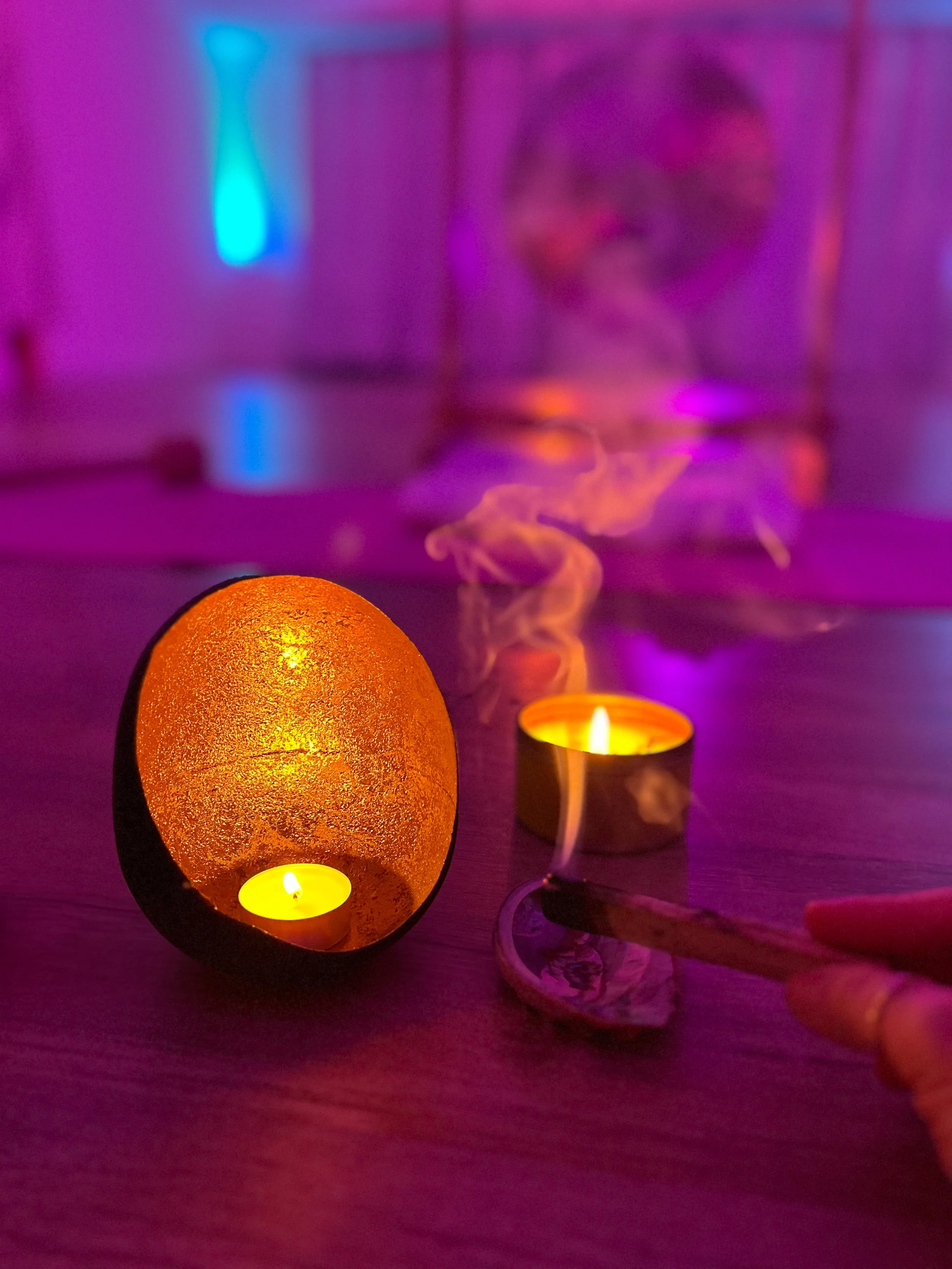 Palo Santos und Räucherwerk mit Kerzen in einer bunt beleuchteten Atmosphäre.