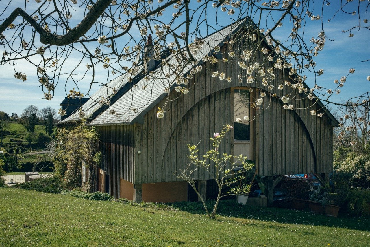 Extension en bois au pignon courbe d’une maison en pierre à Villerville.