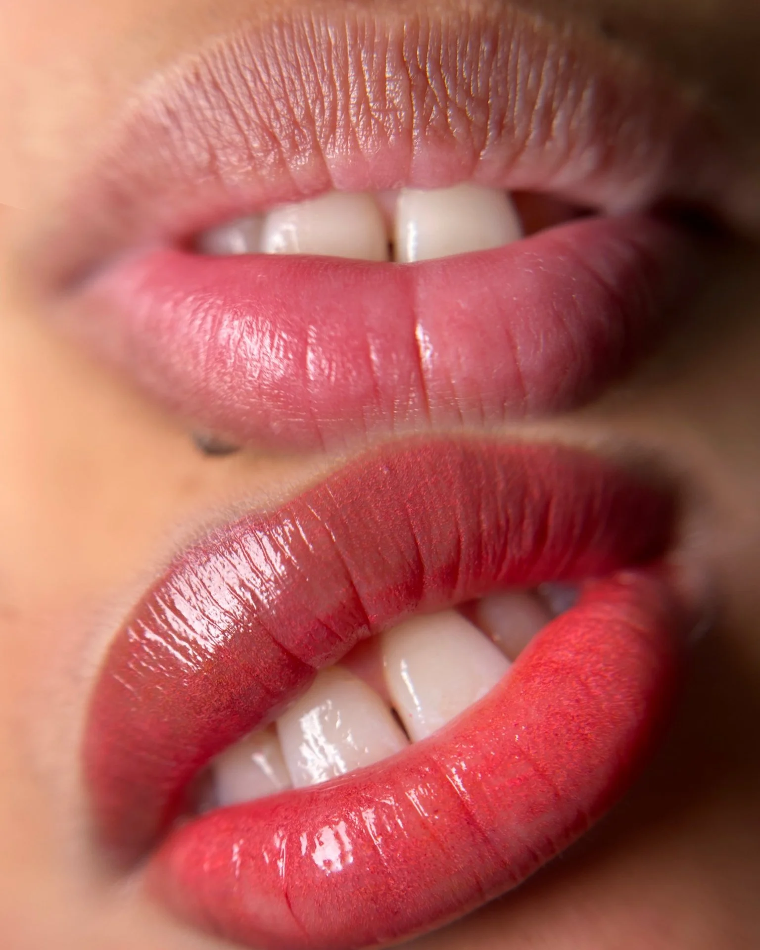 Close-up of lips with pink lipstick, showing teeth and a part of a smile.