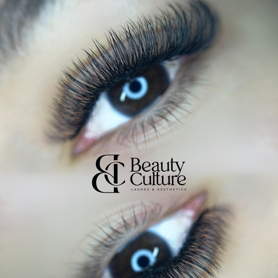 Close-up of a person's eye with long, thick eyelashes and a reflection of a light in the pupil. The image has a logo for 'Beauty & Culture Lash & Aesthetics' overlaid.