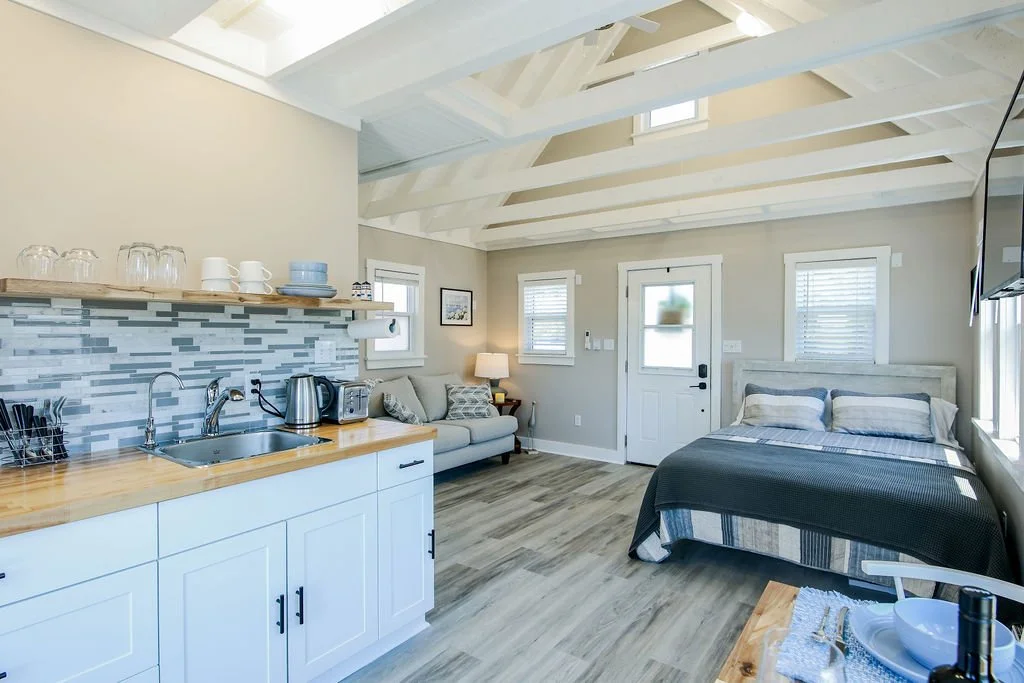 Open-concept studio with kitchen, seating area, and bed in a bright, modern room.