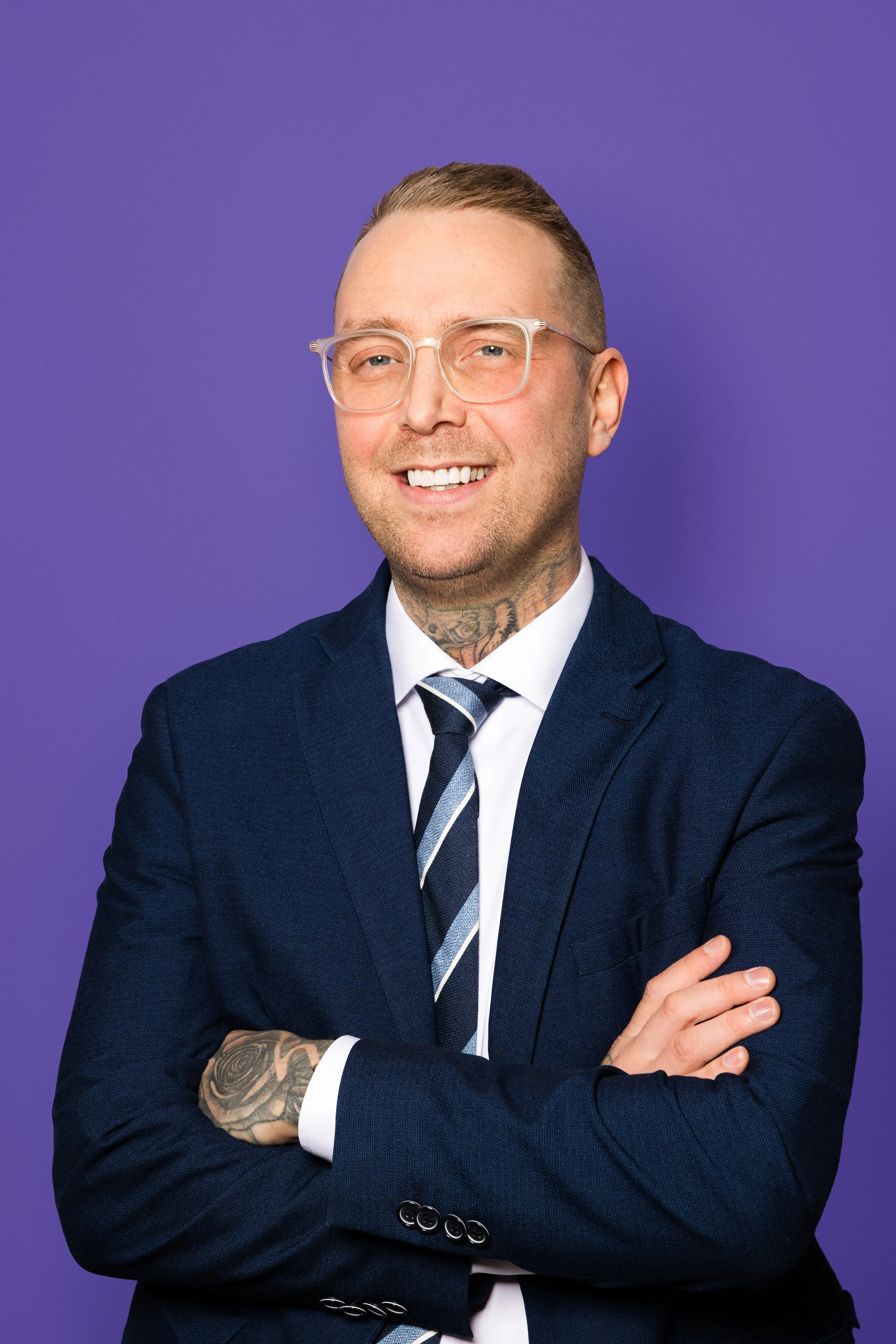 Unnar brosir í bláum jakkafötum með ljós gleraugu