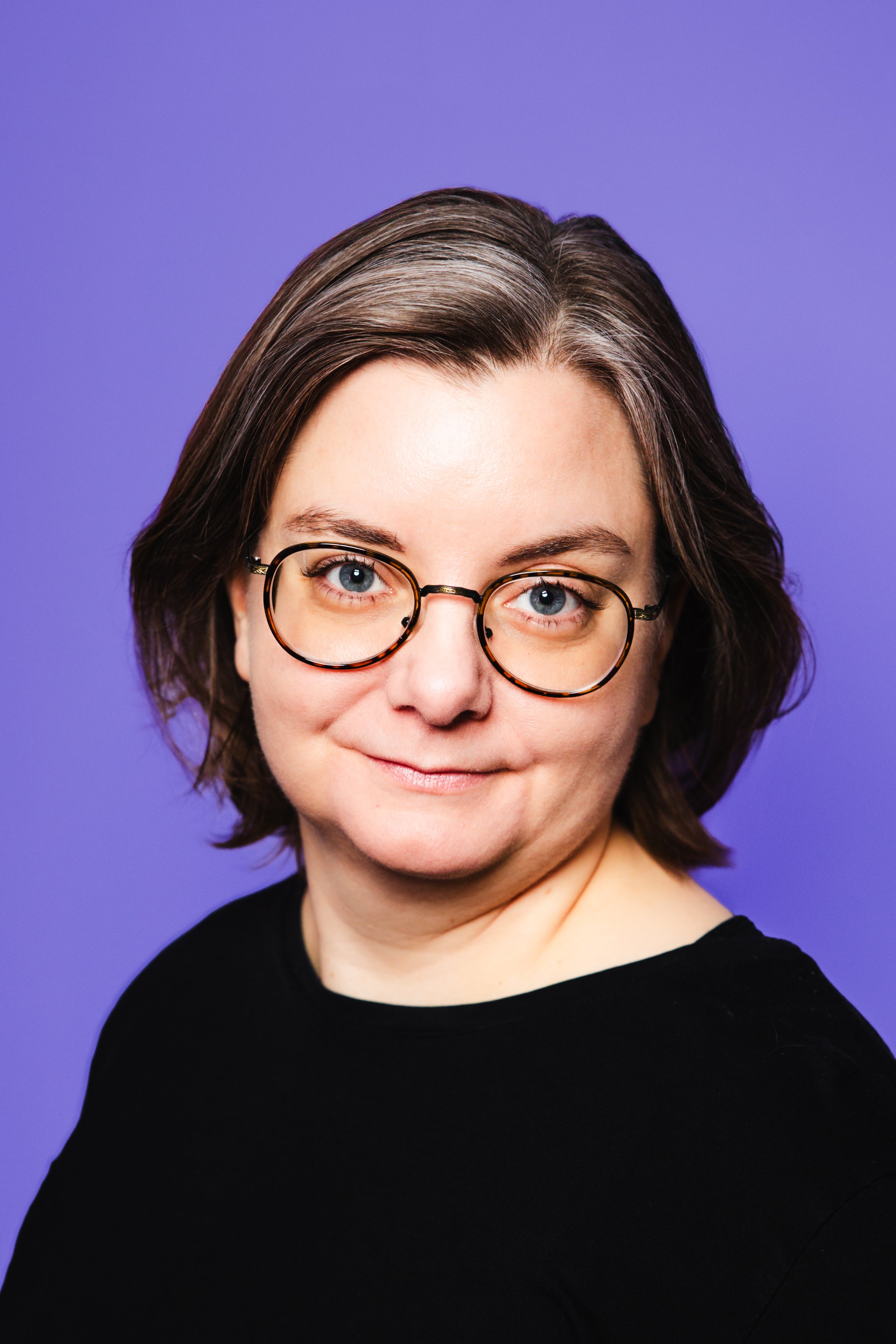 Olga brosir með dökkt hár og gleraugu