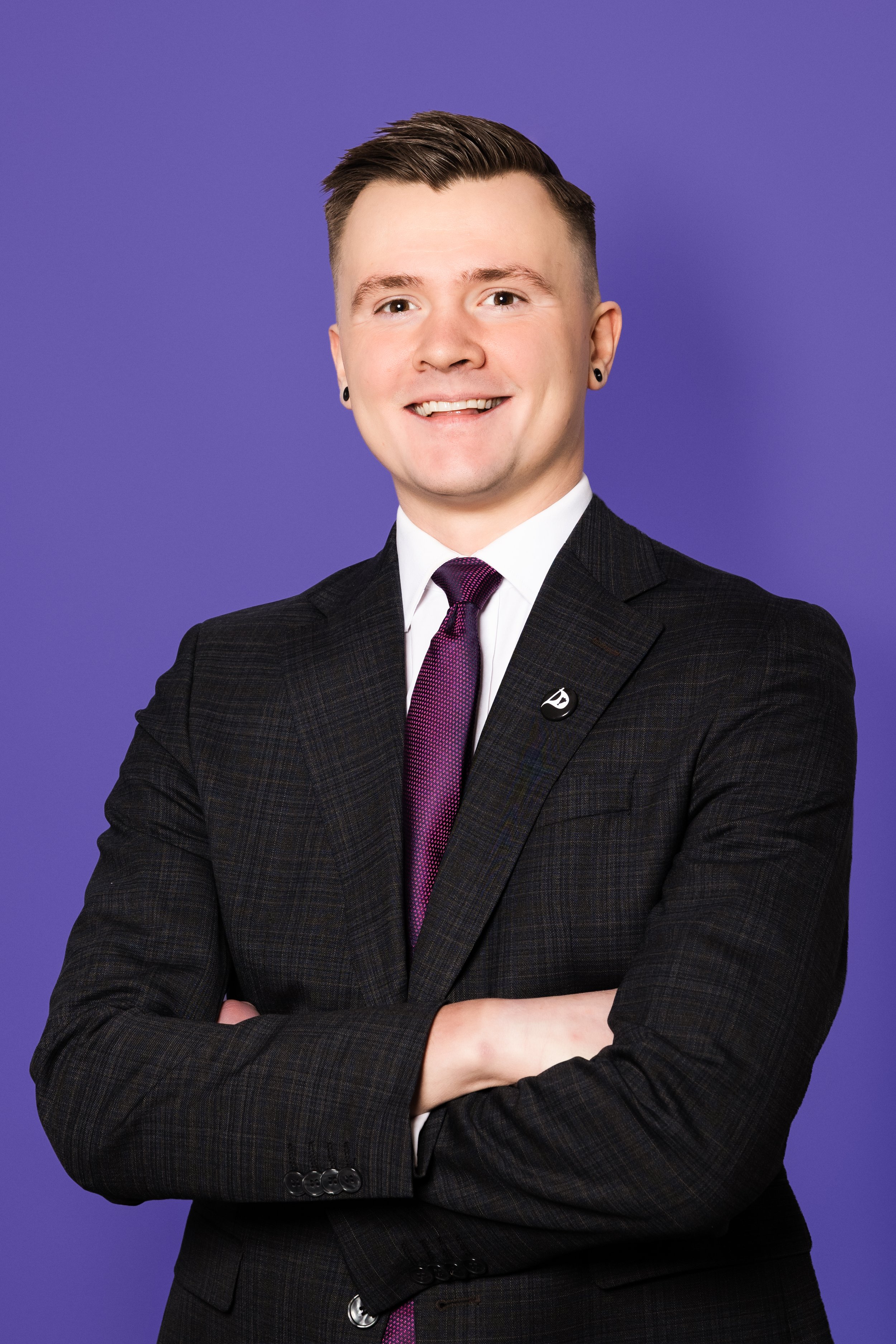 Jökull brosir í dökkum jakkafötum með fjólublátt bindi og píratanælu